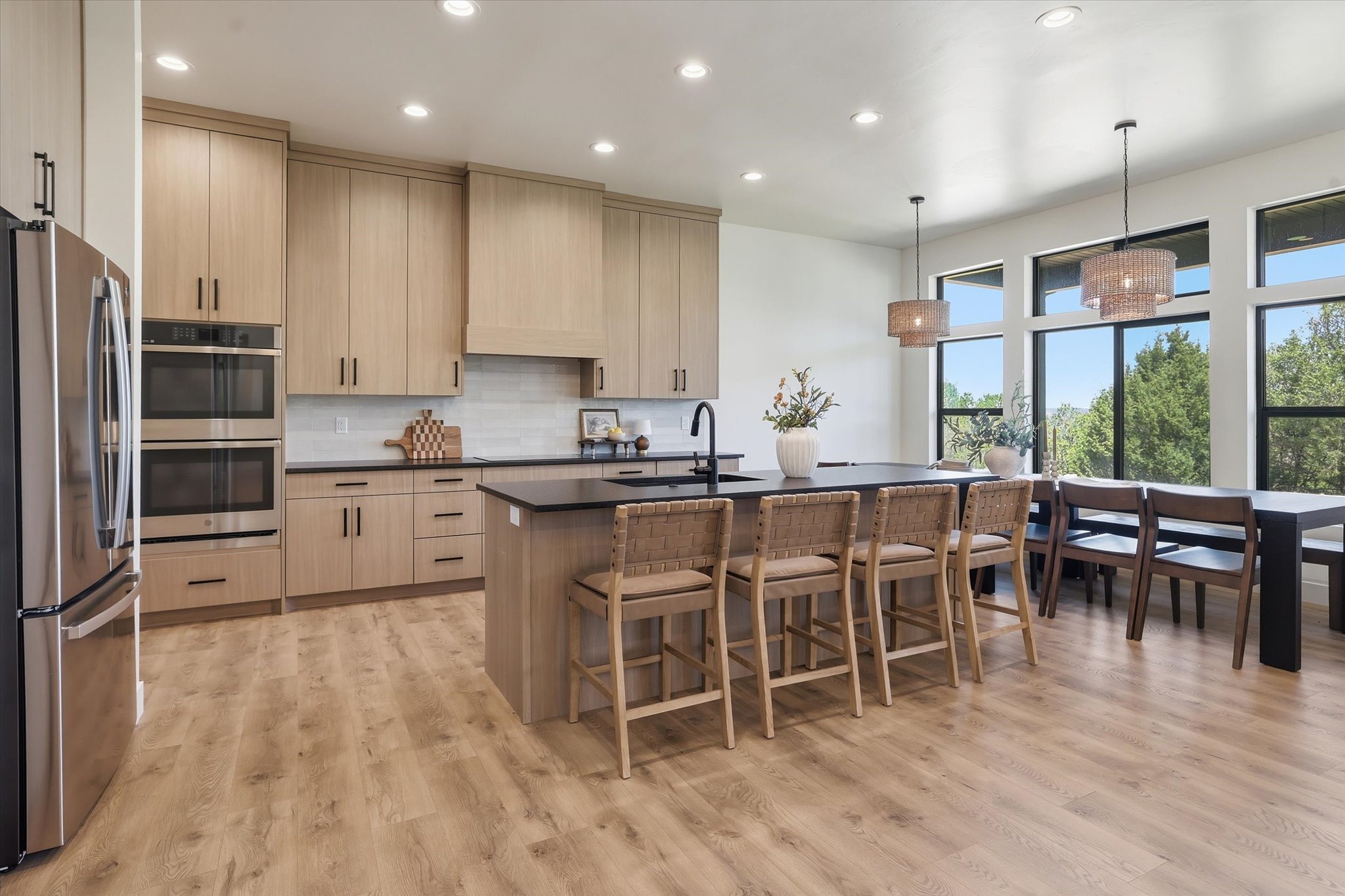 Kitchen featuring light wood-finish cabinetry, black countertops, and a full stainless steel appliance suite