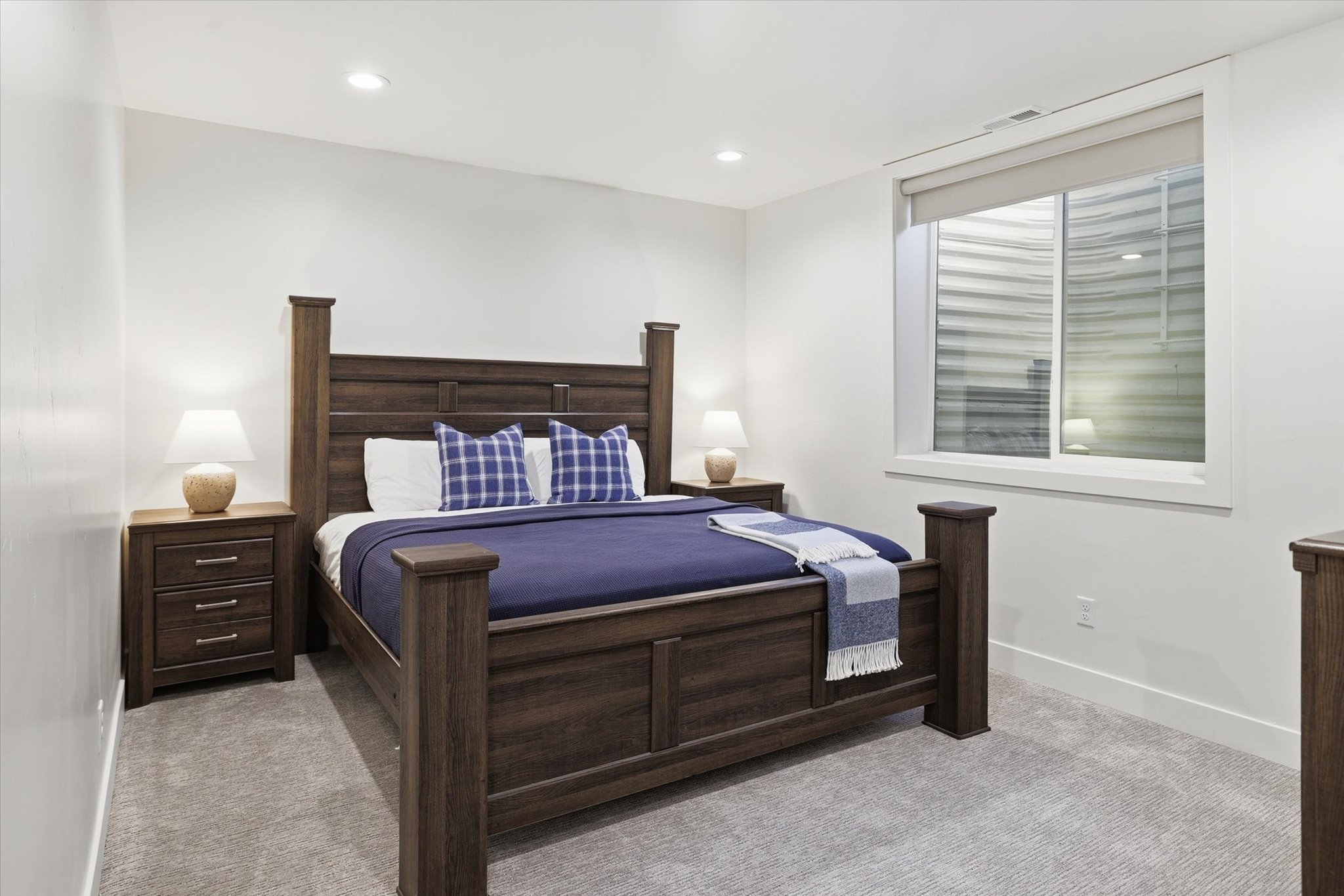 Spacious room featuring neutral carpeting, a large egress window with roller shade, recessed lighting, and white walls