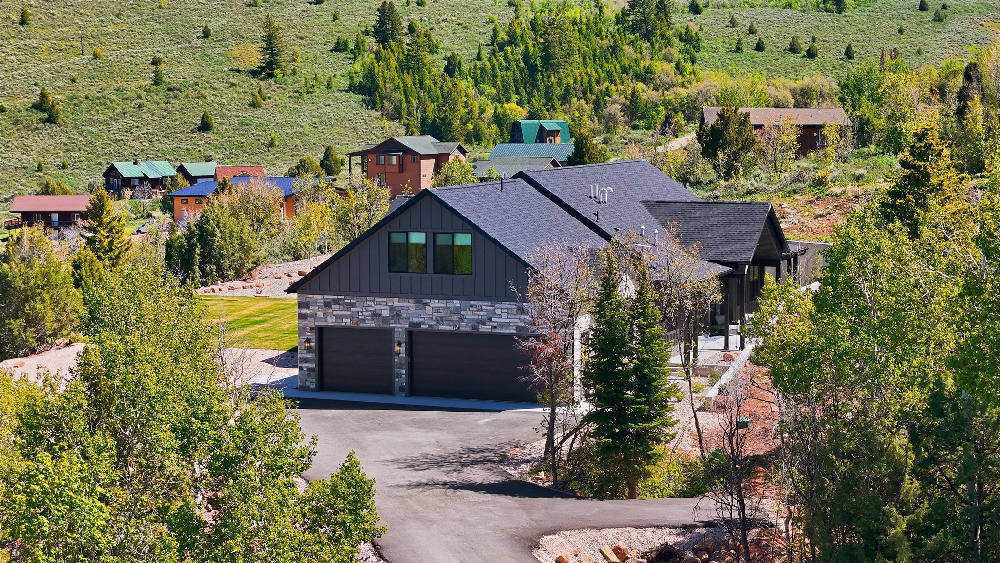 Contemporary home with a dark gray shingle roof, stone veneer, and vertical dark siding