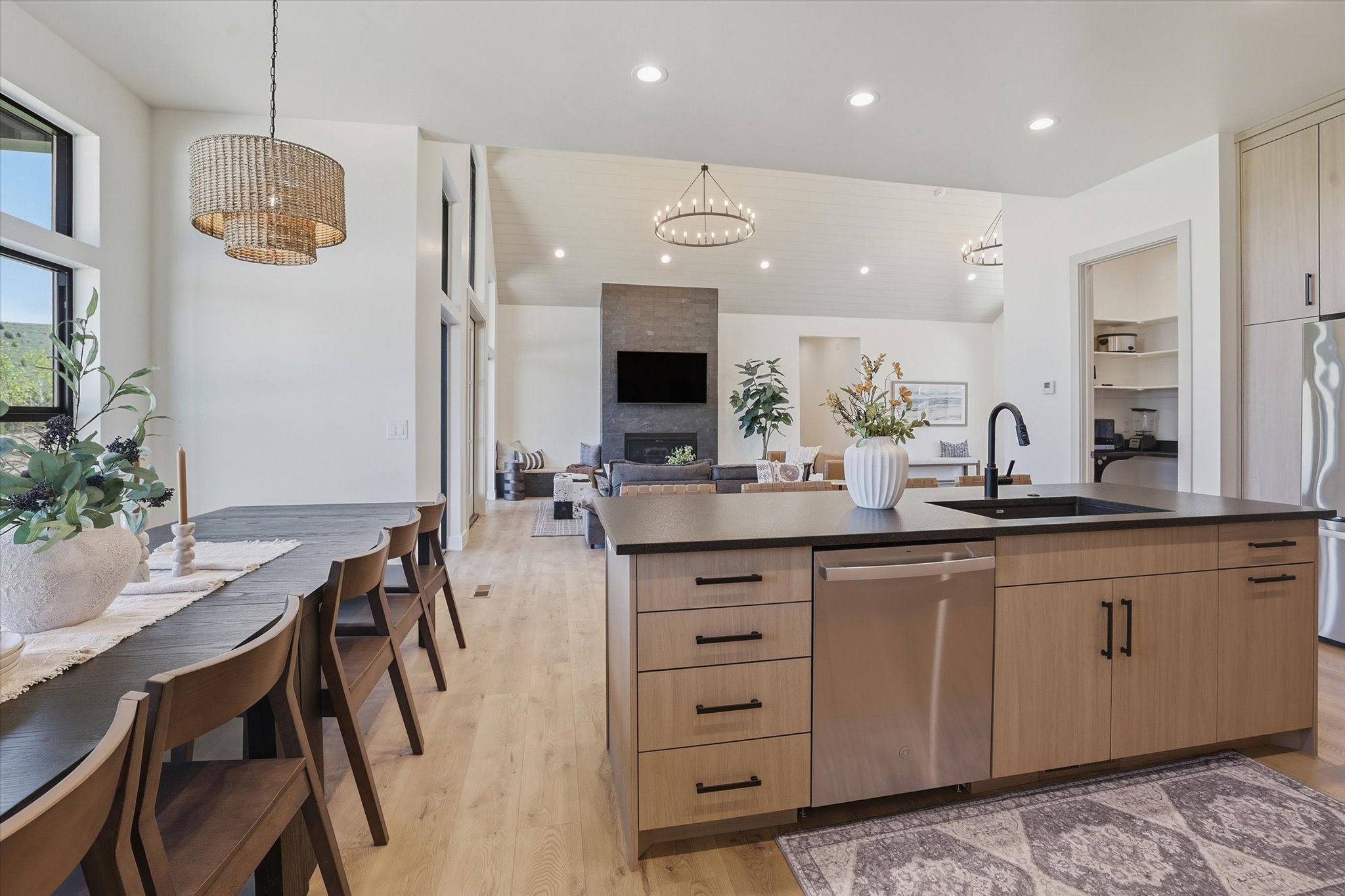 Spacious kitchen featuring a large island with a black sink and matte black faucet, light wood-finish cabinetry, stainless steel appliances, and dark countertops