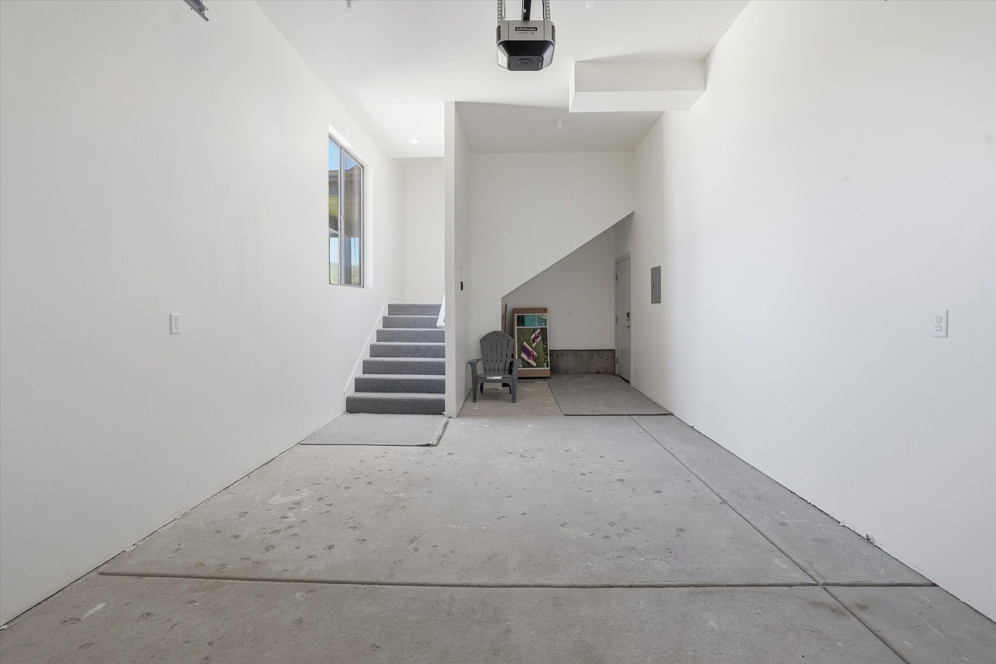 Spacious garage with concrete flooring, white painted walls, and an overhead garage door opener