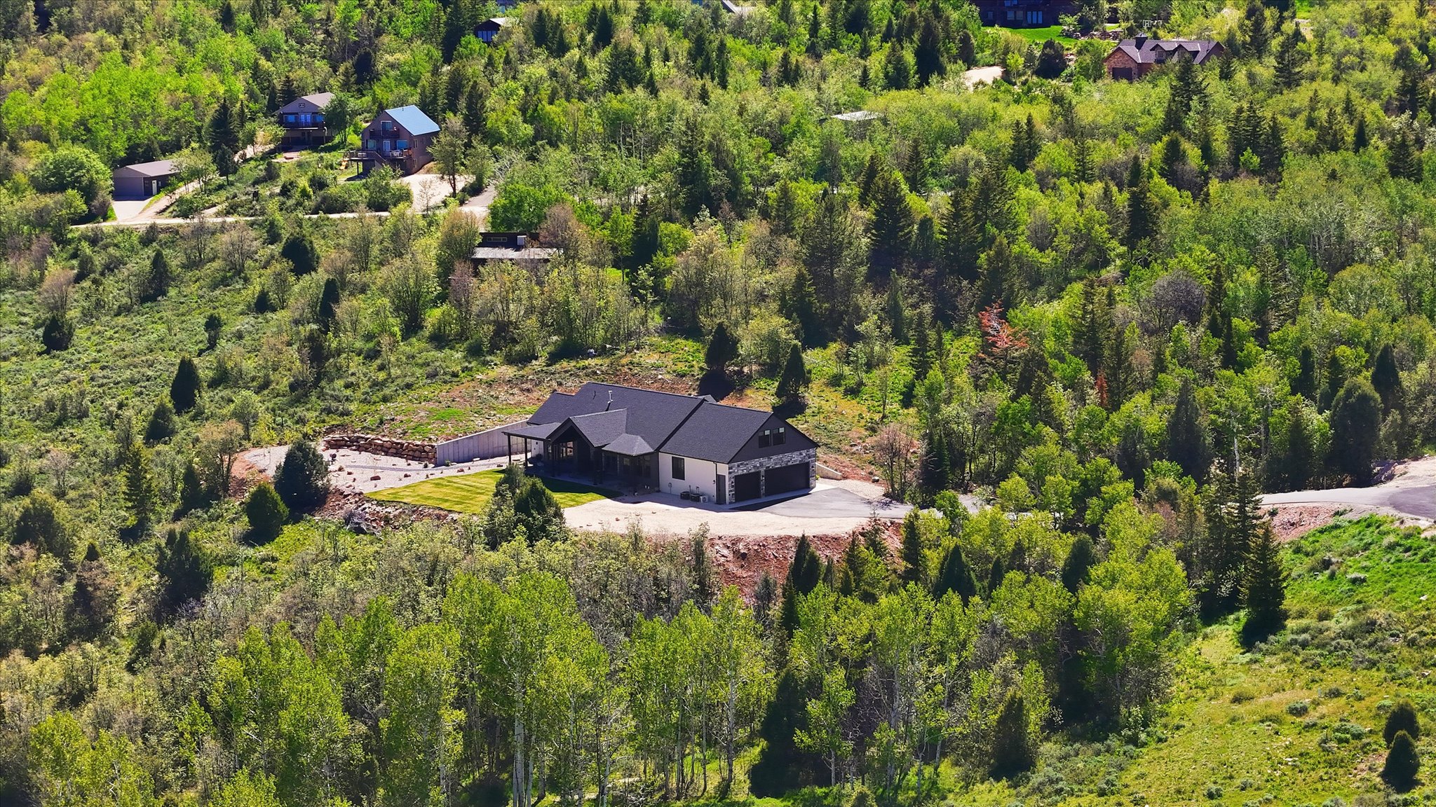Modern ranch-style residence featuring a dark shingle roof, light-toned siding, and a two-car garage
