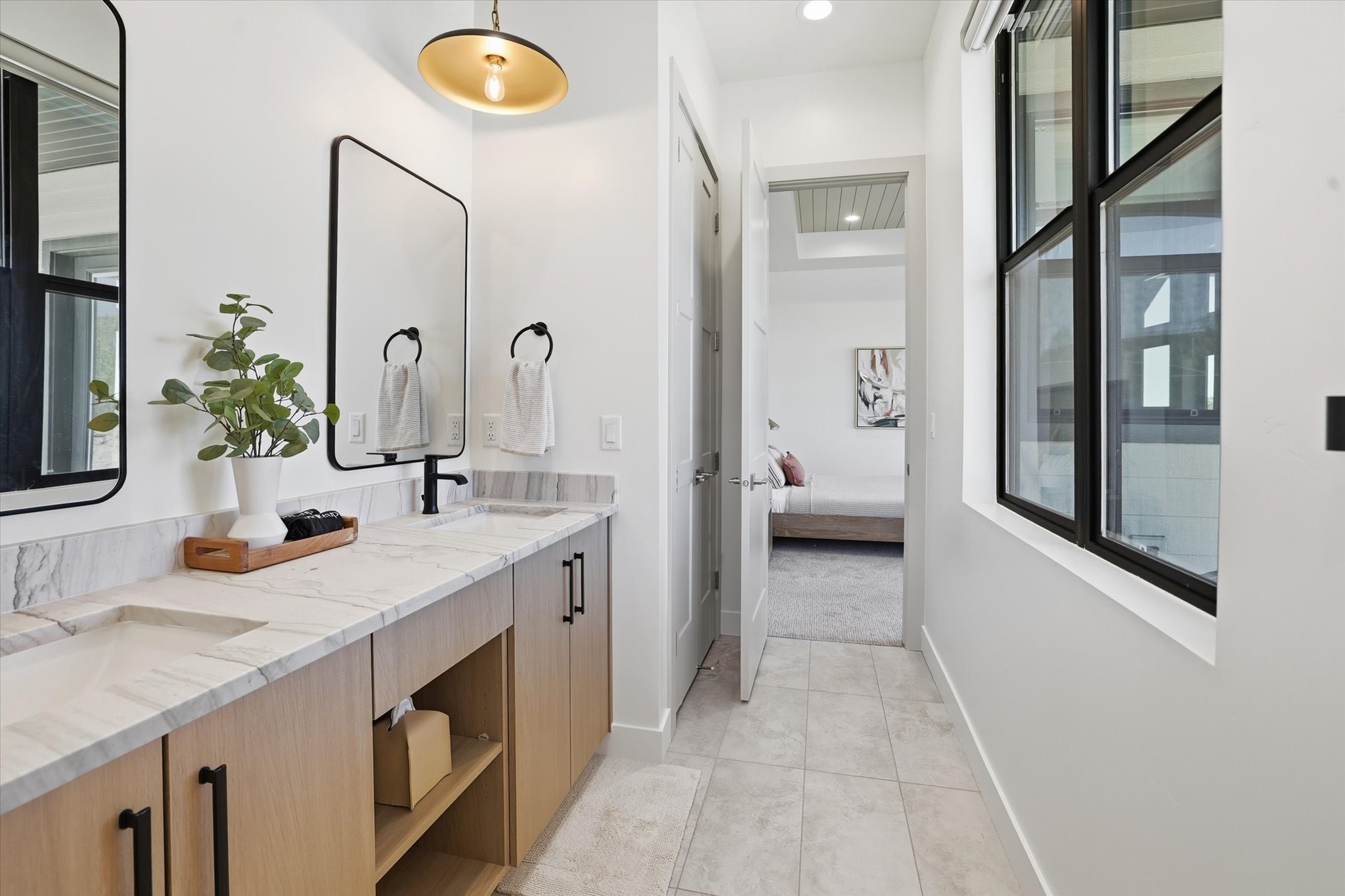 Double vanity with light wood-finish cabinetry, integrated sinks, and polished countertops