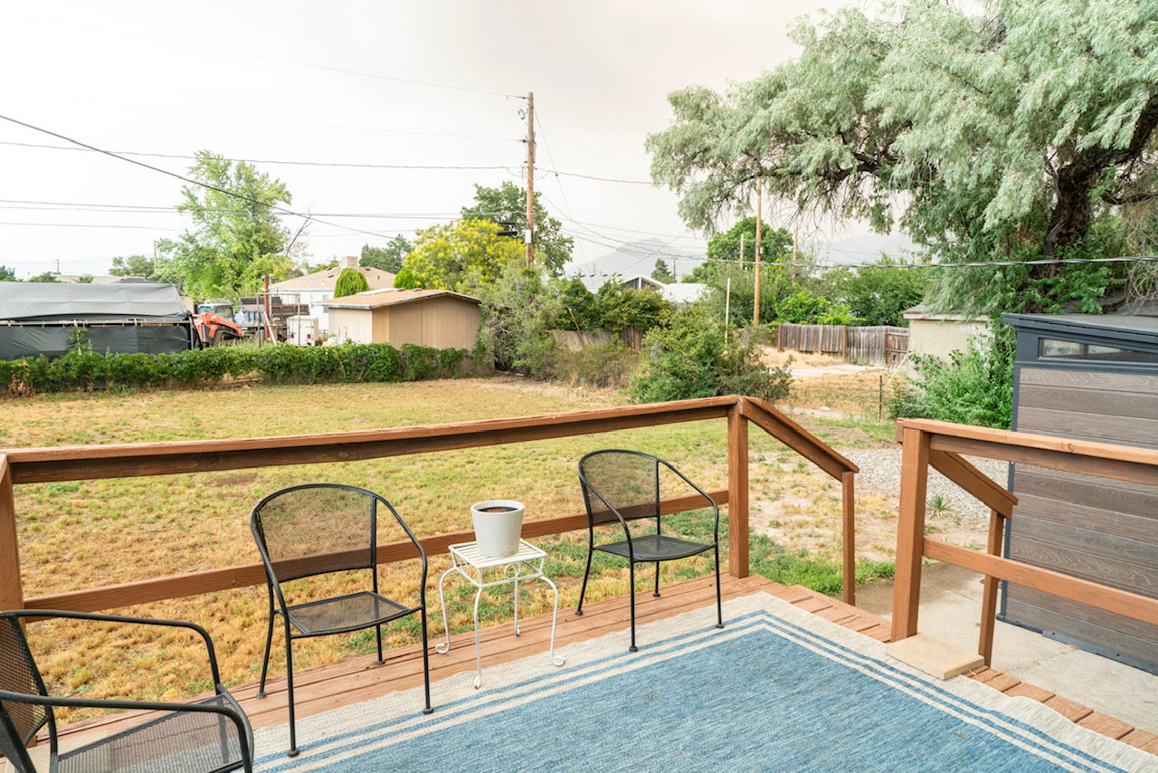 Expansive wood-decked patio featuring a wood railing and stairs leading to the yard