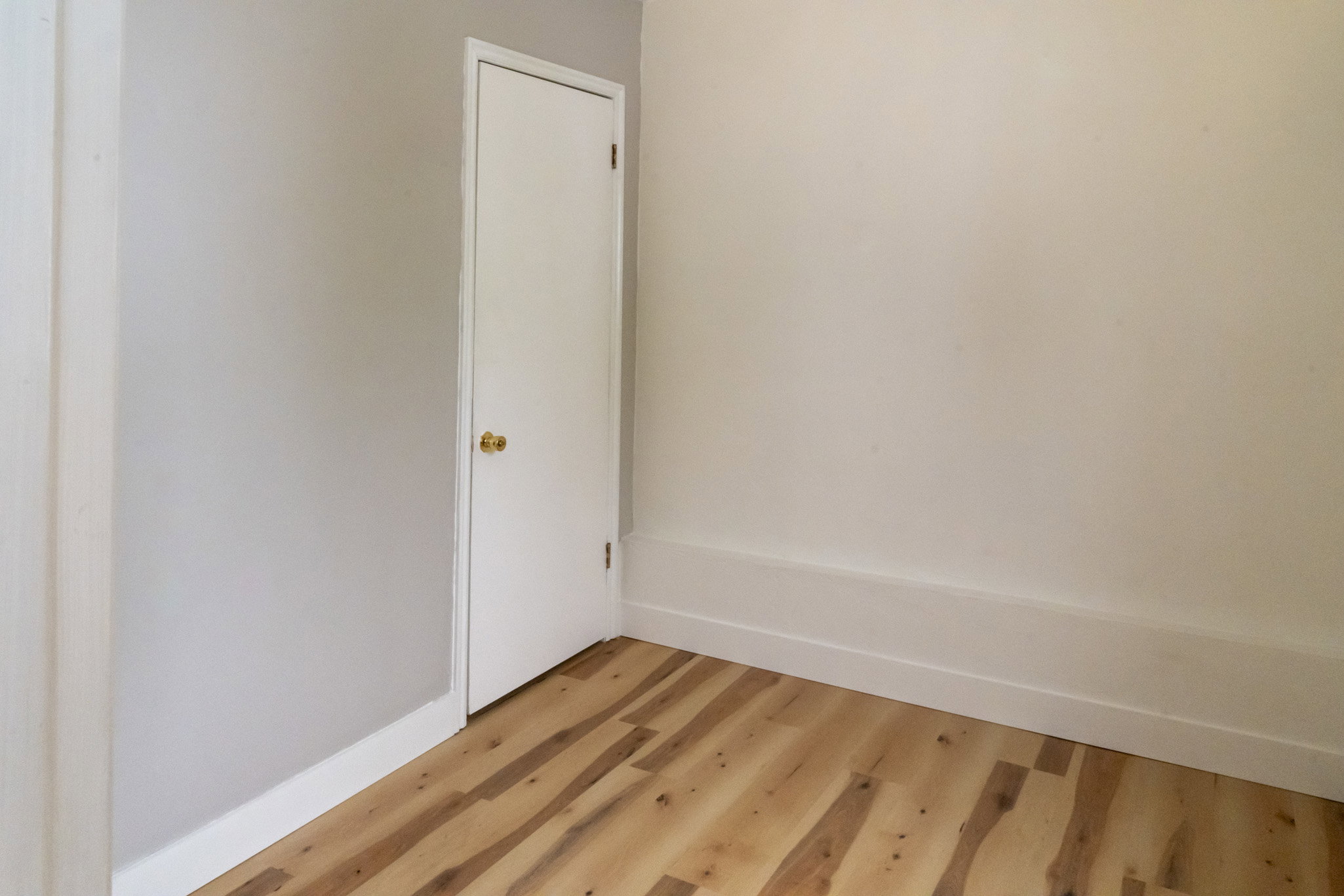 Room featuring wood-finish flooring, white baseboards, and two-tone wall paint
