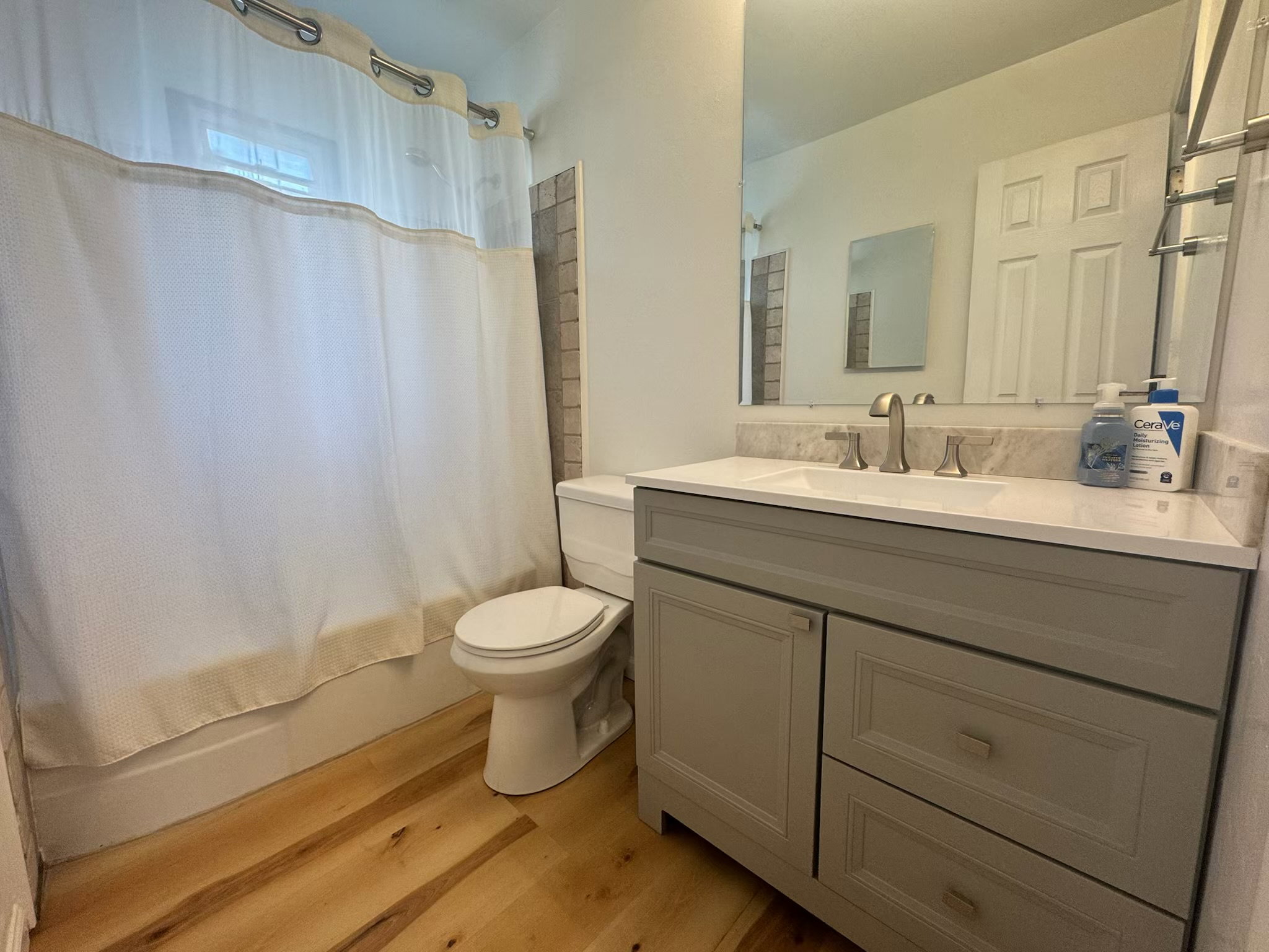 Bathroom featuring a grey vanity with a white countertop, undermount sink, and brushed nickel faucet