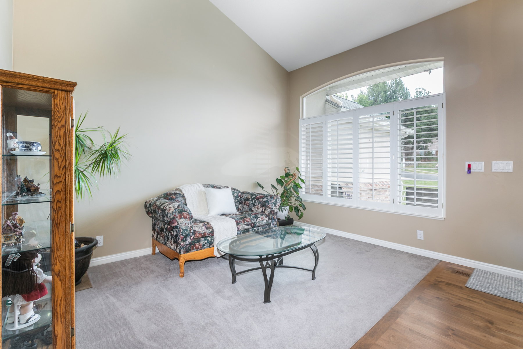 Living area featuring a vaulted ceiling and an arched window with white plantation shutters