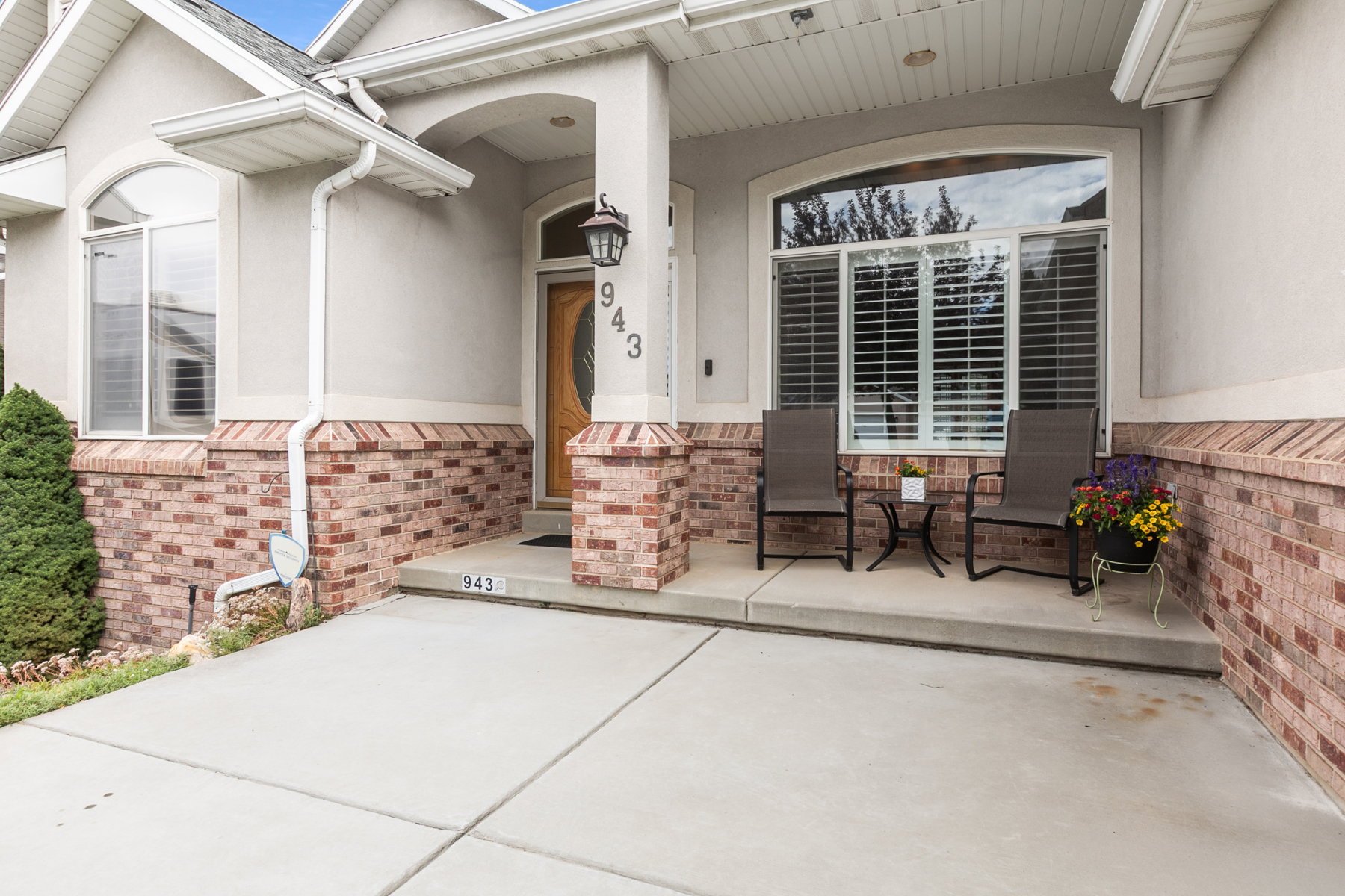 Inviting front entrance featuring a covered porch, brick veneer accents, an arched entryway, and an oval glass-paneled door