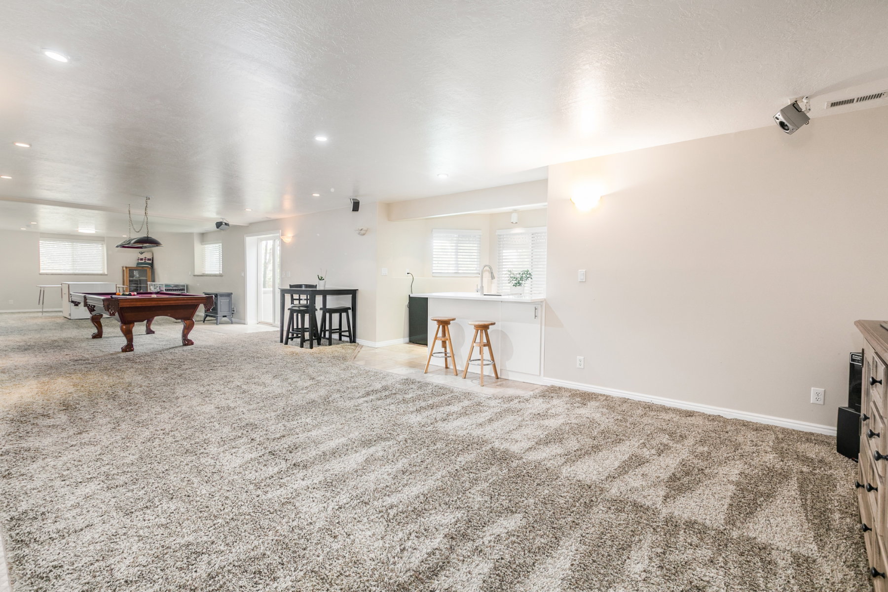 Spacious finished basement featuring light gray carpet flooring and recessed lighting