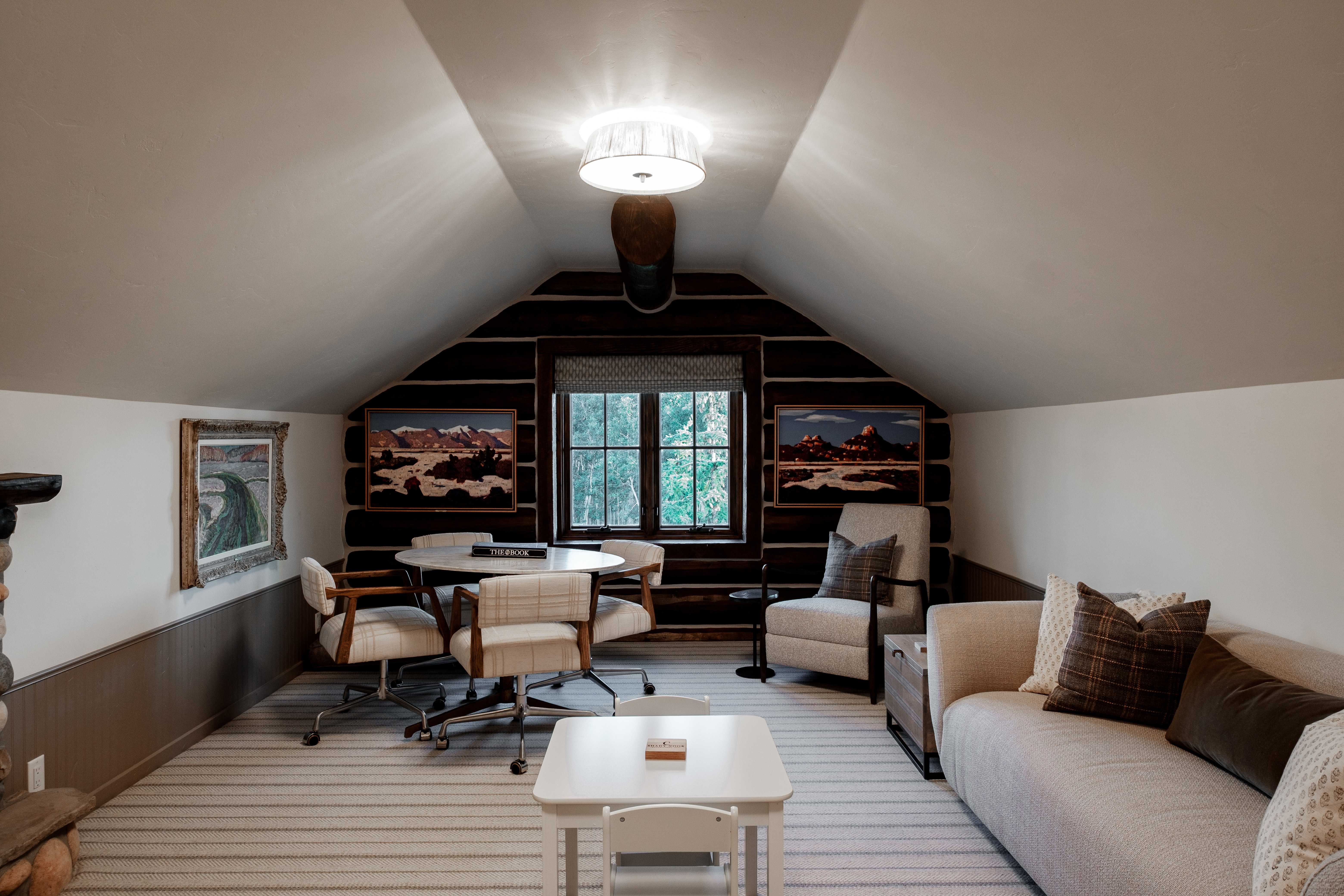 Attic room with sloped ceilings, featuring a dark wood-finish log wall and a window with a patterned shade