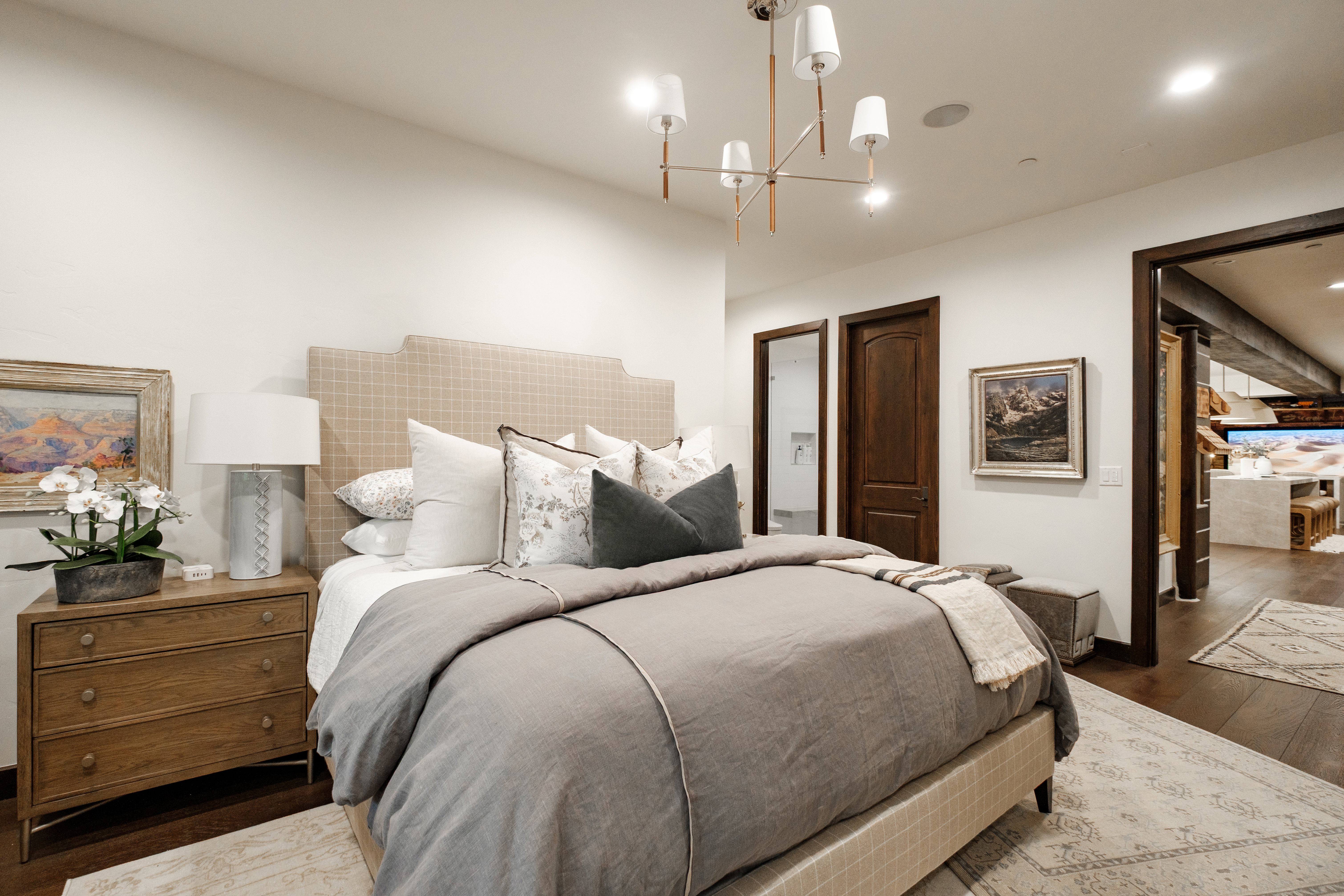 Bedroom featuring dark wood-finish flooring, a contemporary chandelier, recessed lighting, and a plaid upholstered headboard