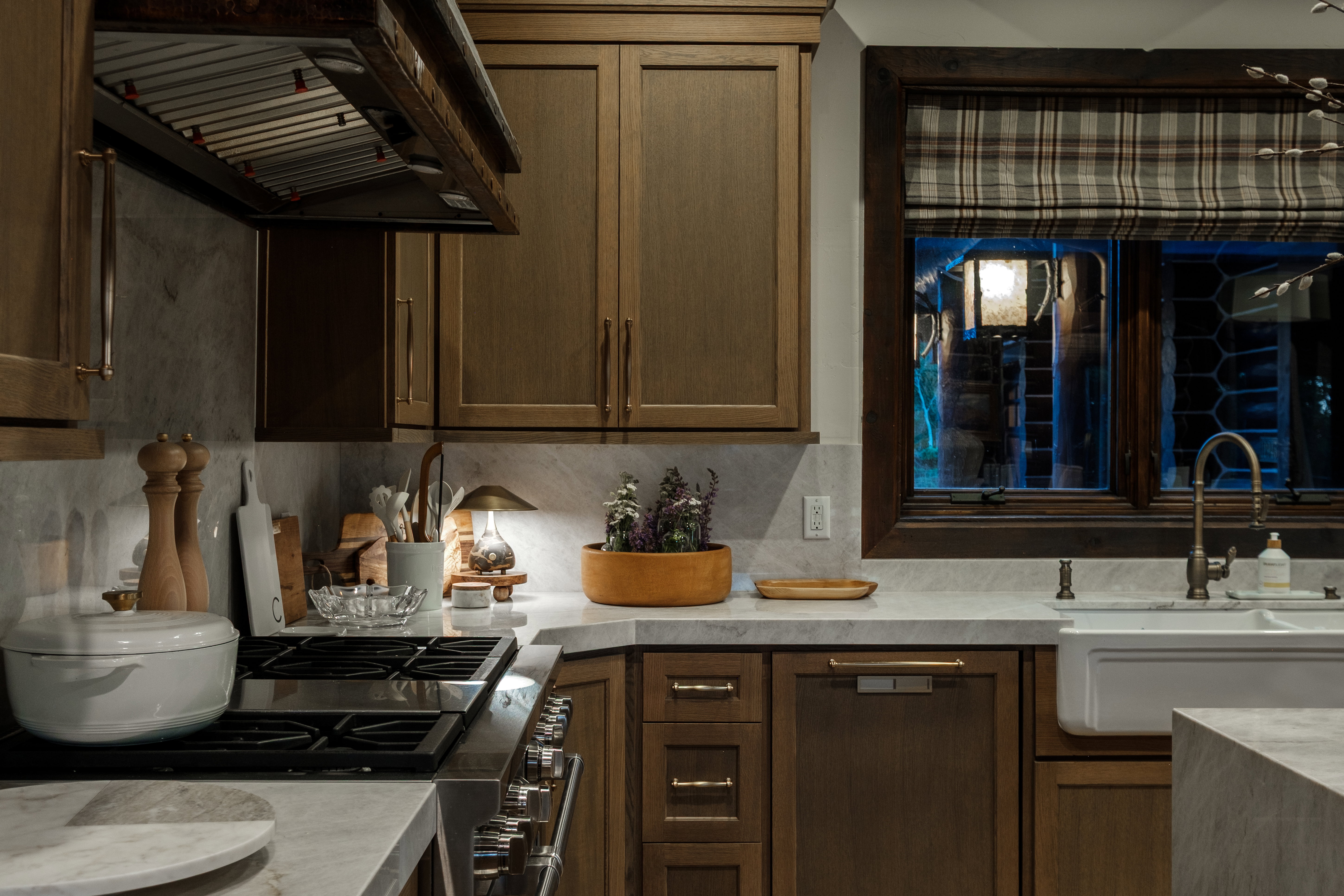 Kitchen featuring wood-finish cabinetry, light-toned countertops, a stainless steel range with overhead ventilation, and a white farmhouse sink