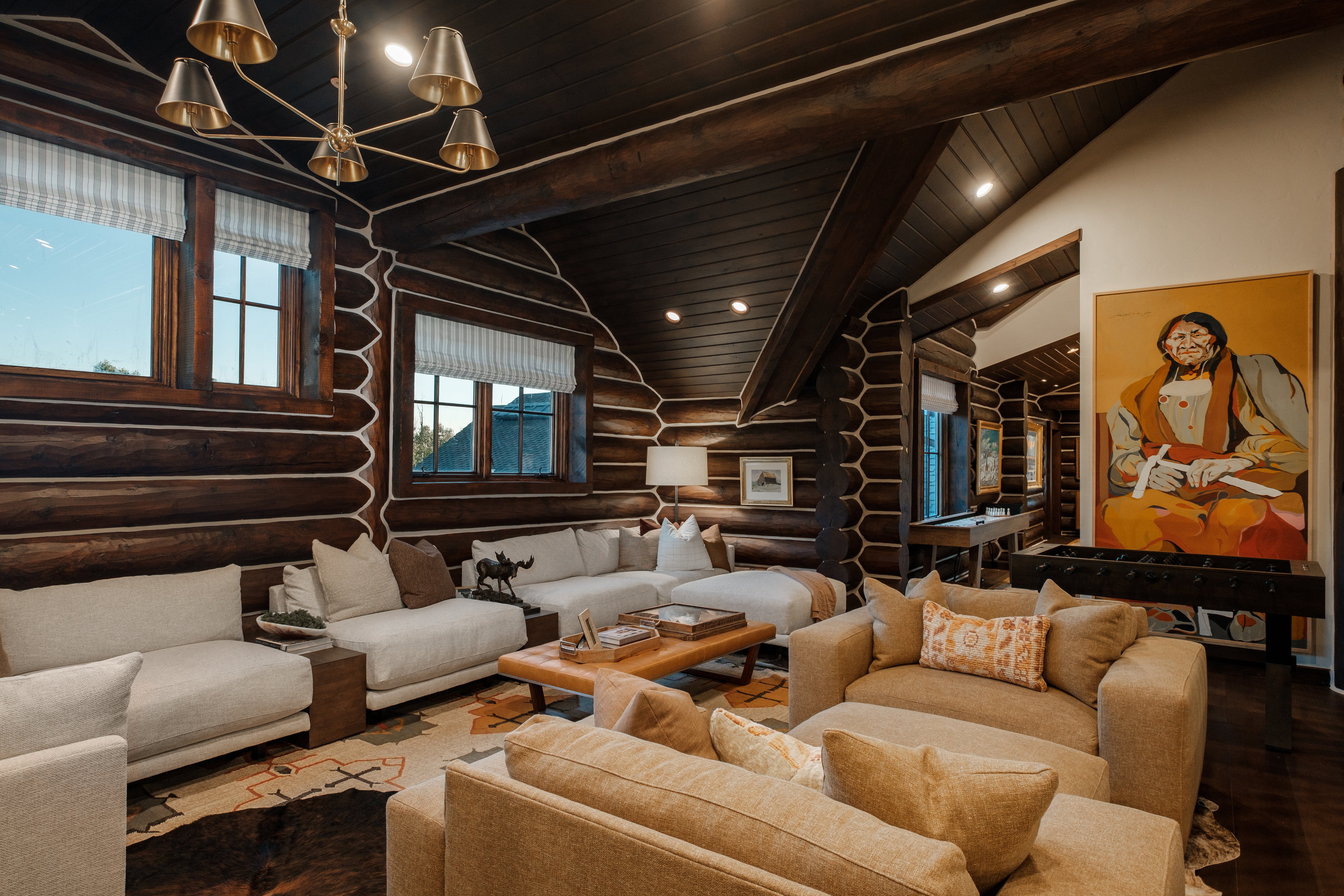 Spacious living area featuring log walls, exposed wood beams, and dark wood-finish flooring