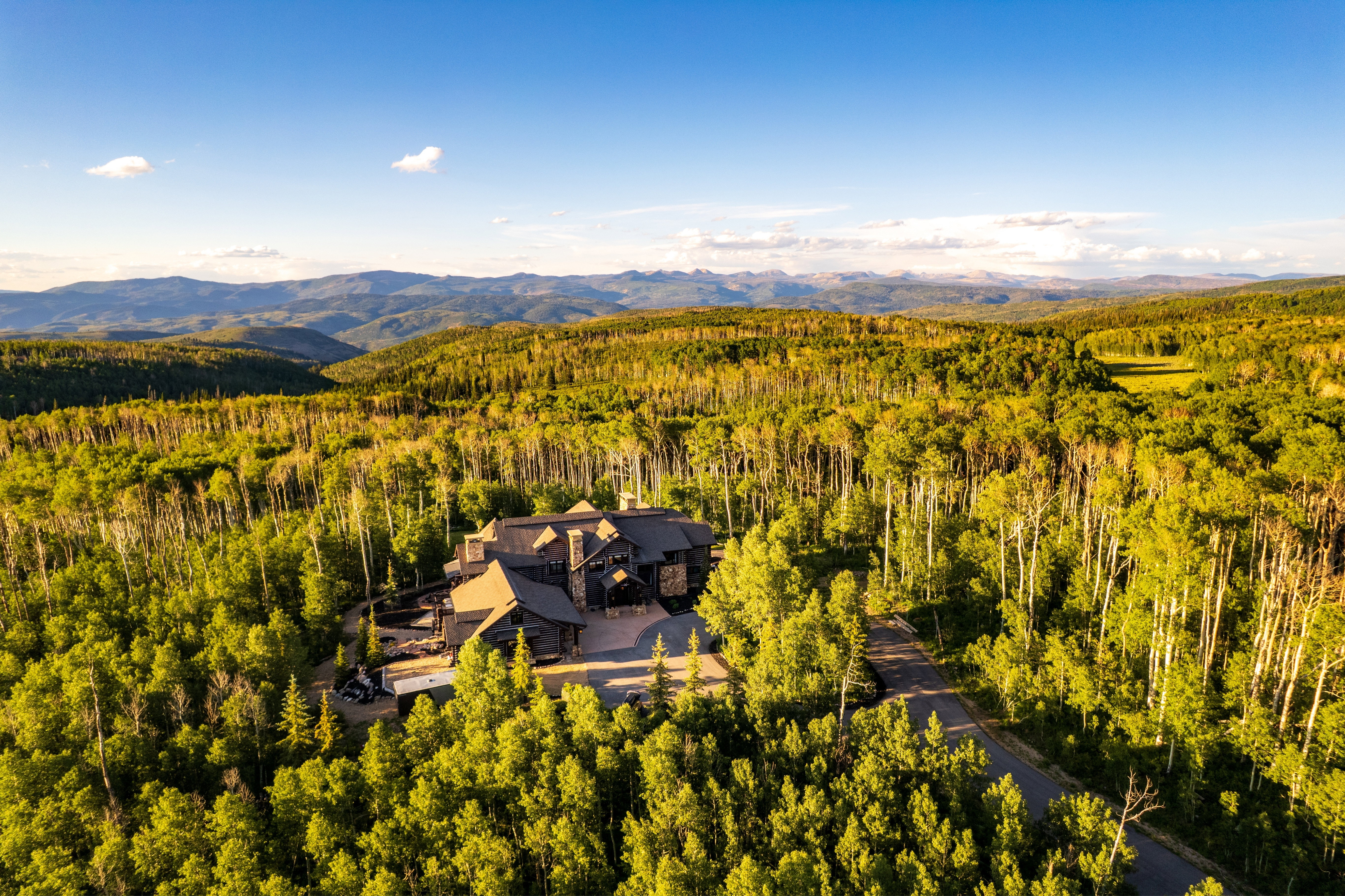 Expansive property featuring a stone and wood-clad exterior, multiple gabled rooflines, and an asphalt driveway