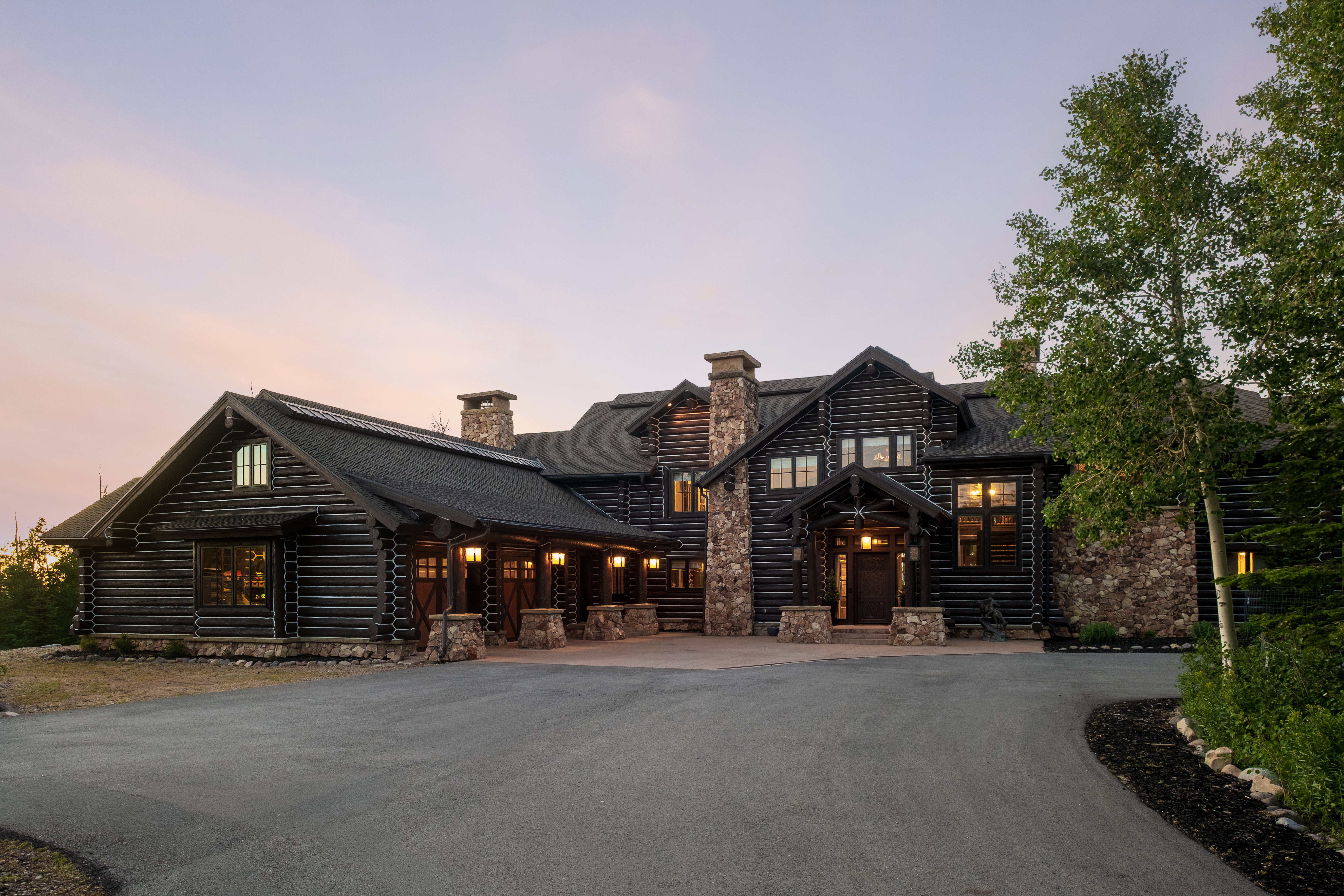 Expansive log home with stone accents and a paved driveway