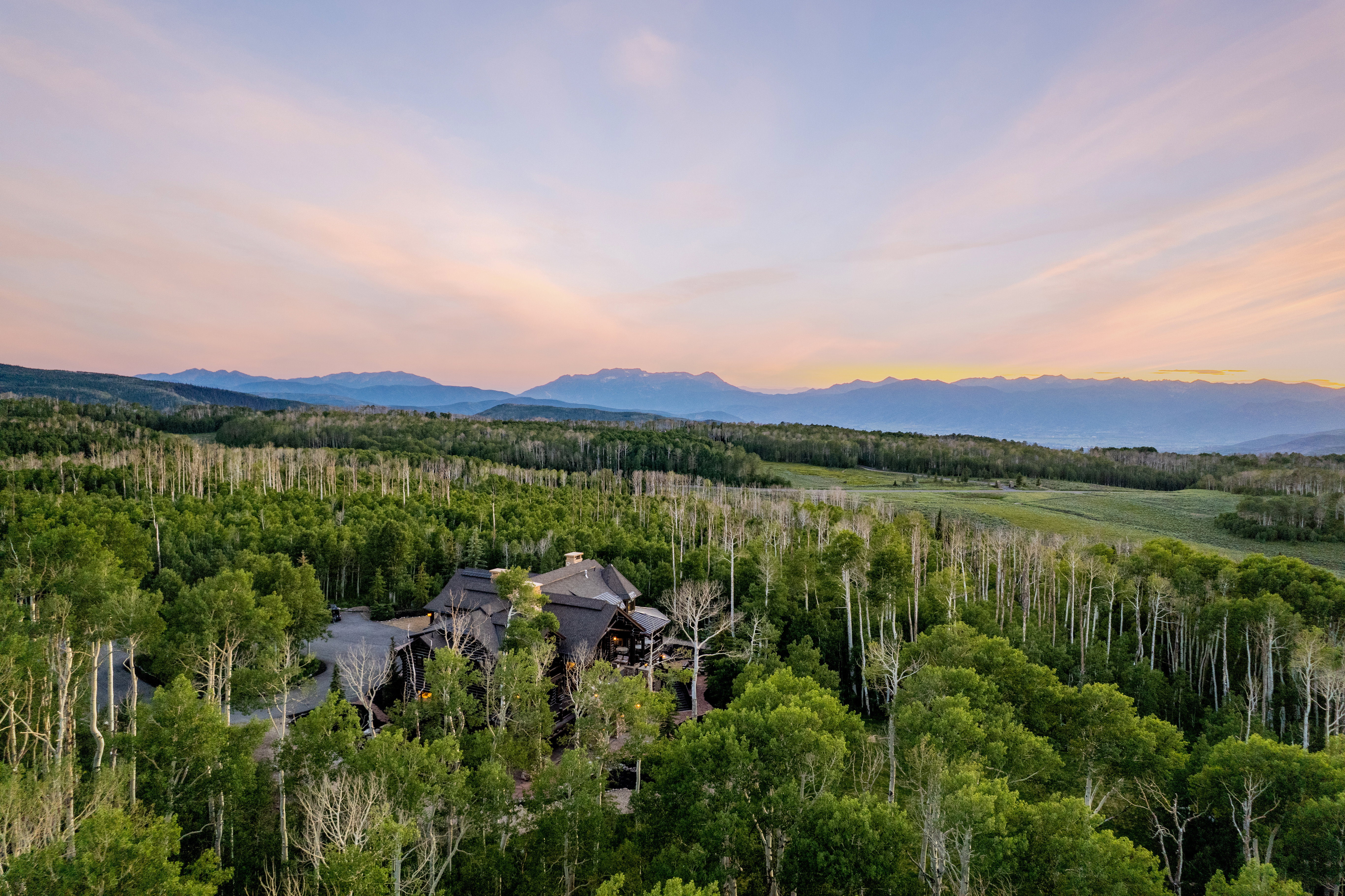 Expansive woodland property featuring a dark-toned residential structure with multiple gables