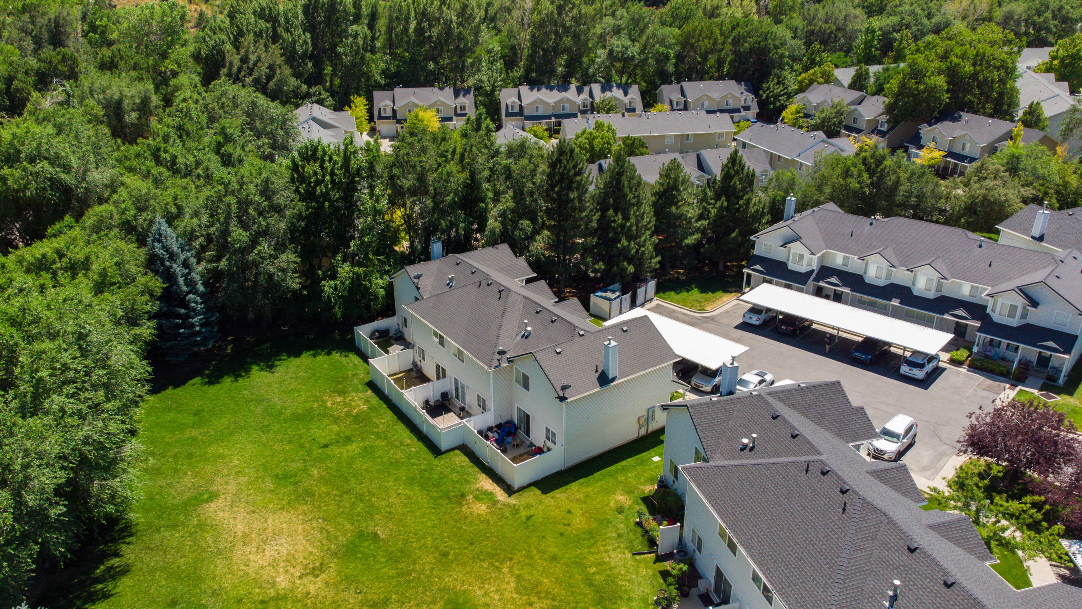 Townhome community featuring white exteriors, dark shingled roofs, and private fenced patios
