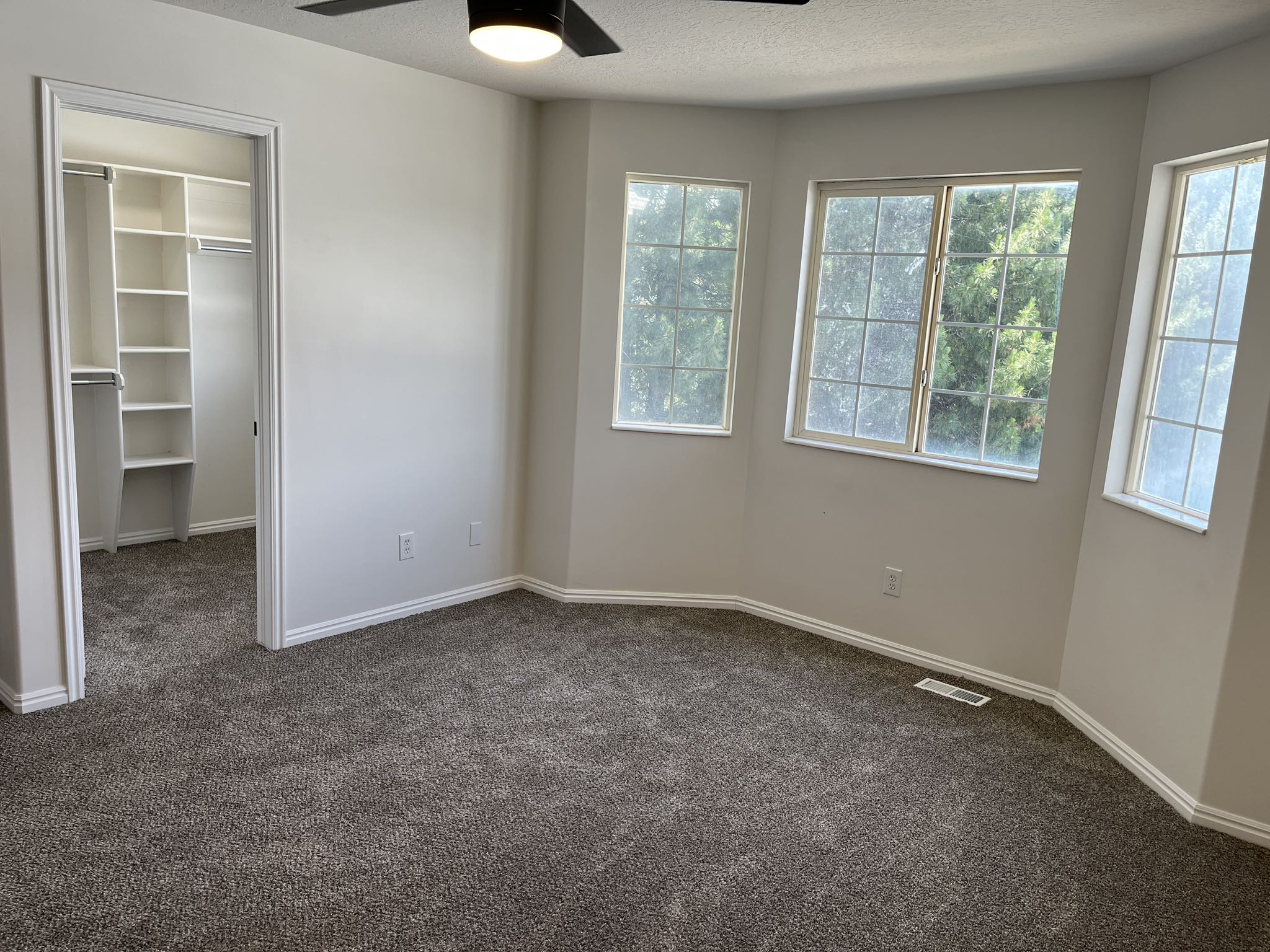 Spacious room with carpet flooring and a ceiling fan light fixture