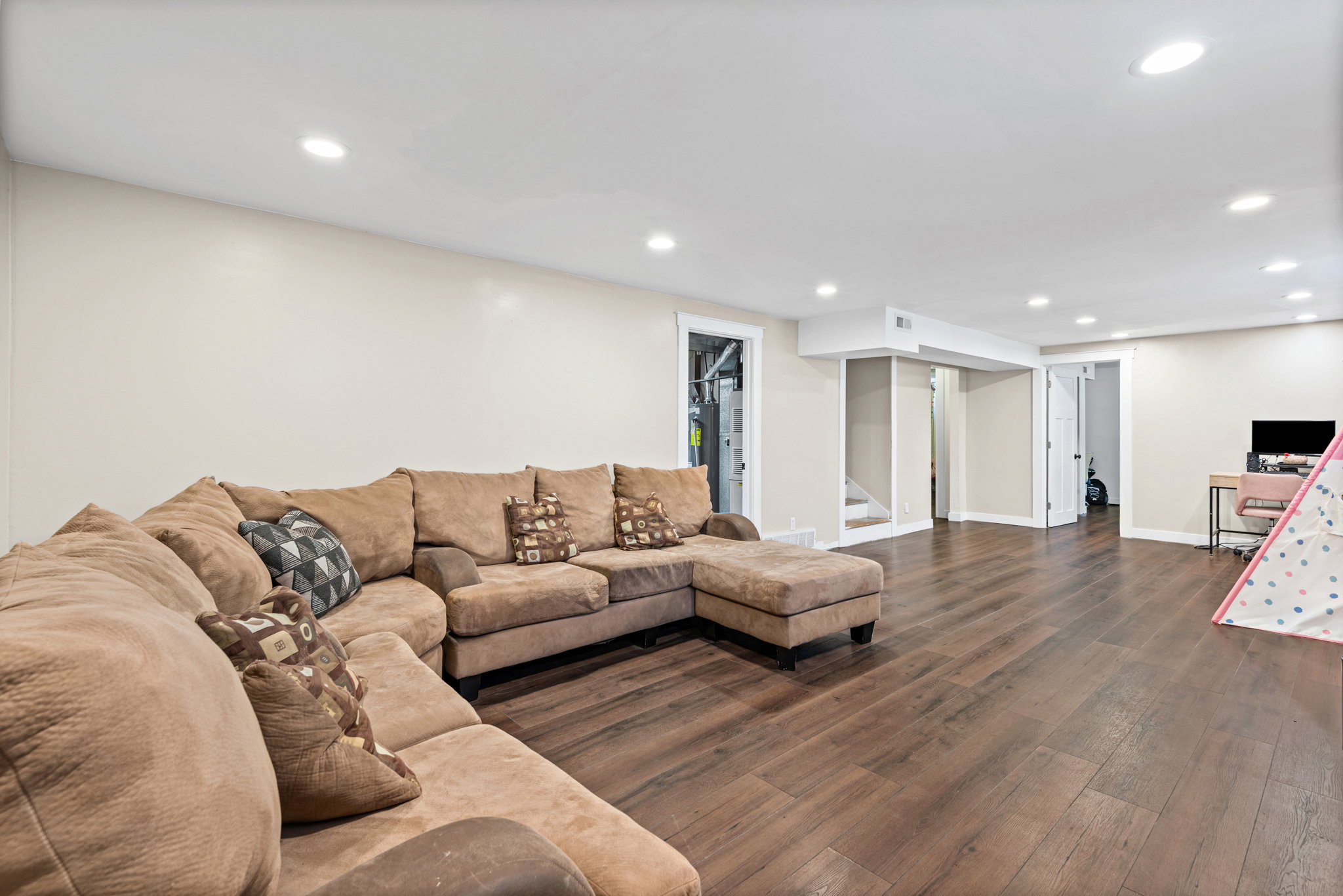 Spacious lower-level area featuring wood-finish flooring, recessed lighting, neutral wall tones, and white trim