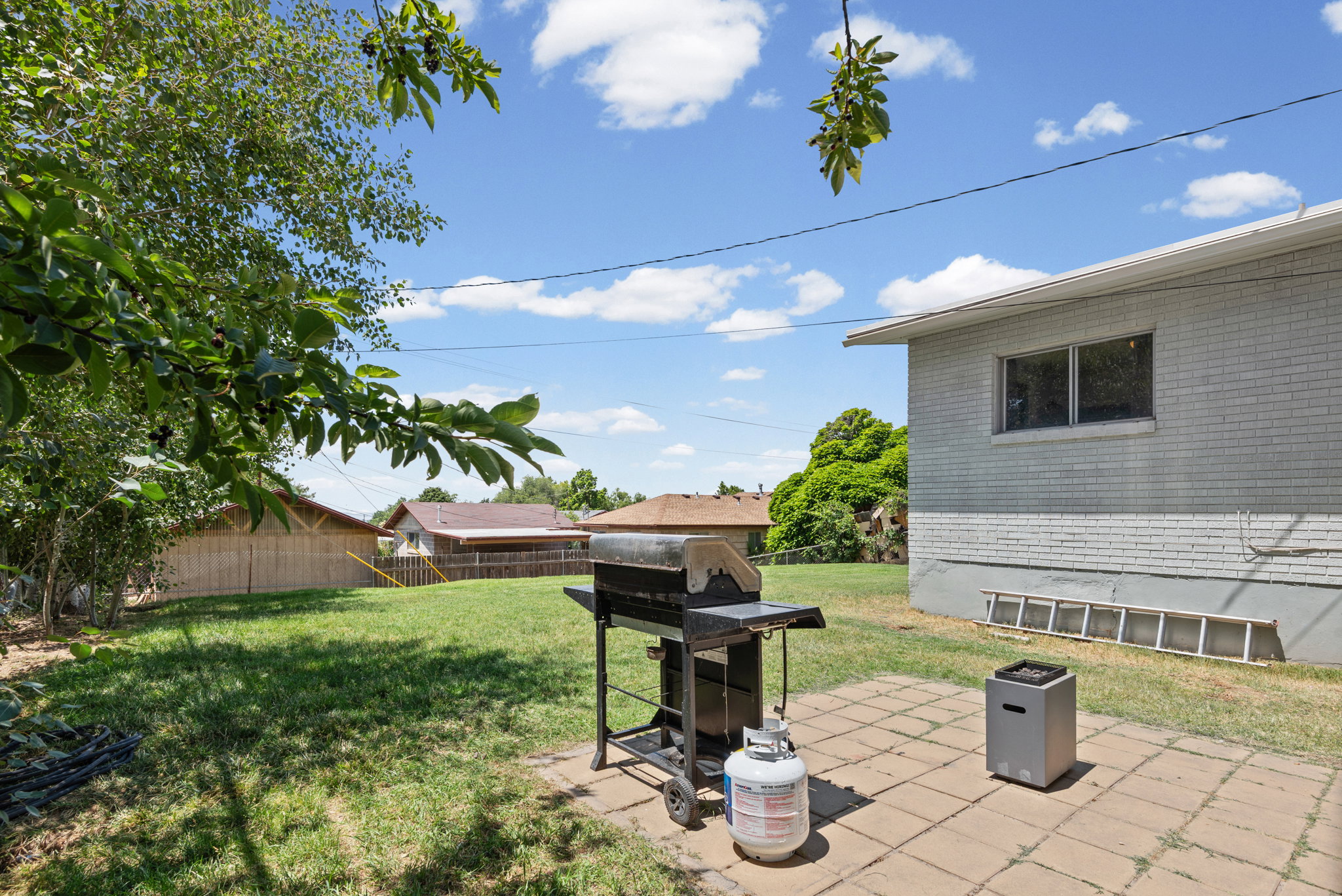 Expansive backyard featuring a concrete paver patio, a wide lawn, and mature trees
