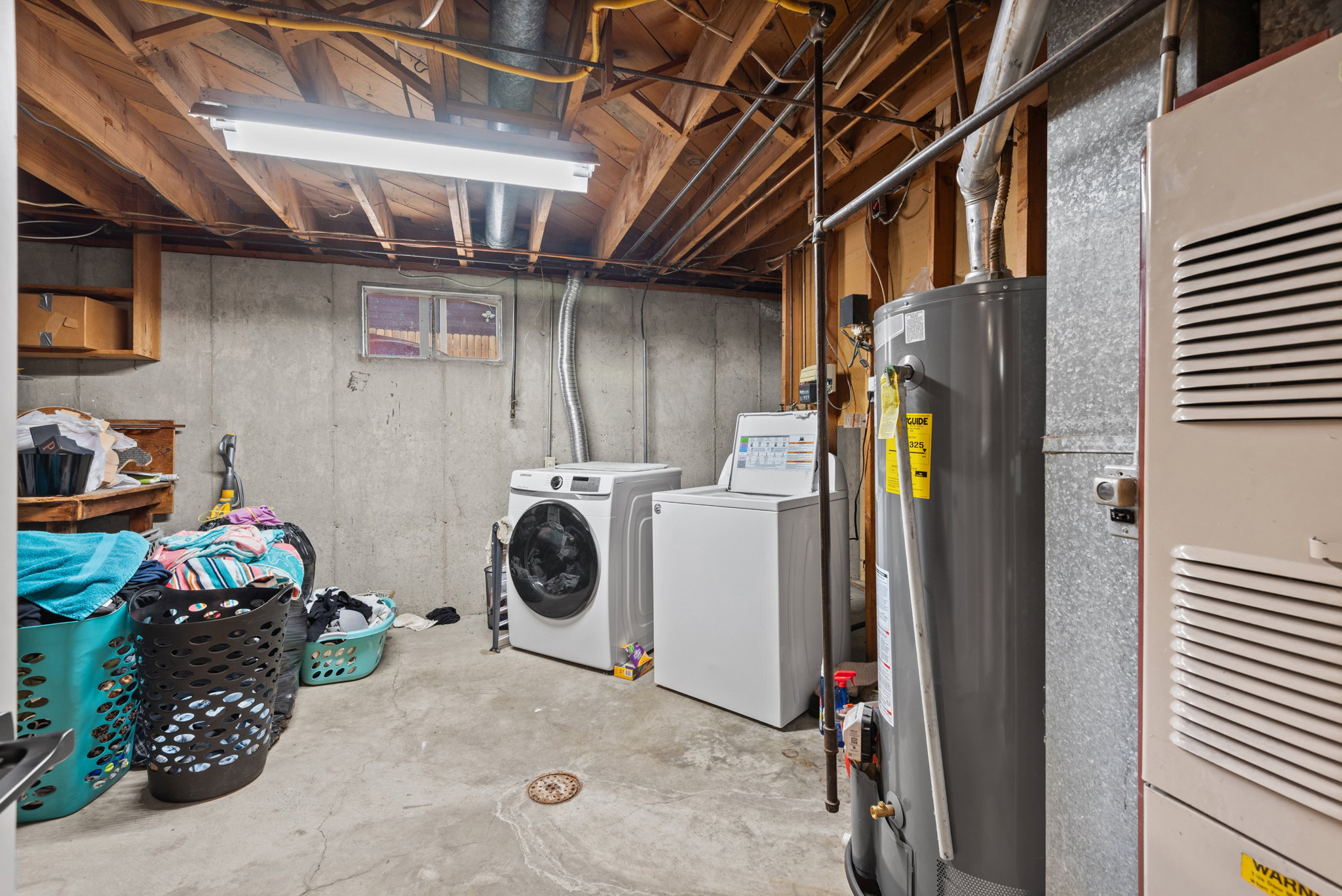 Utility area featuring a concrete floor, exposed joist ceiling, and a fluorescent light fixture