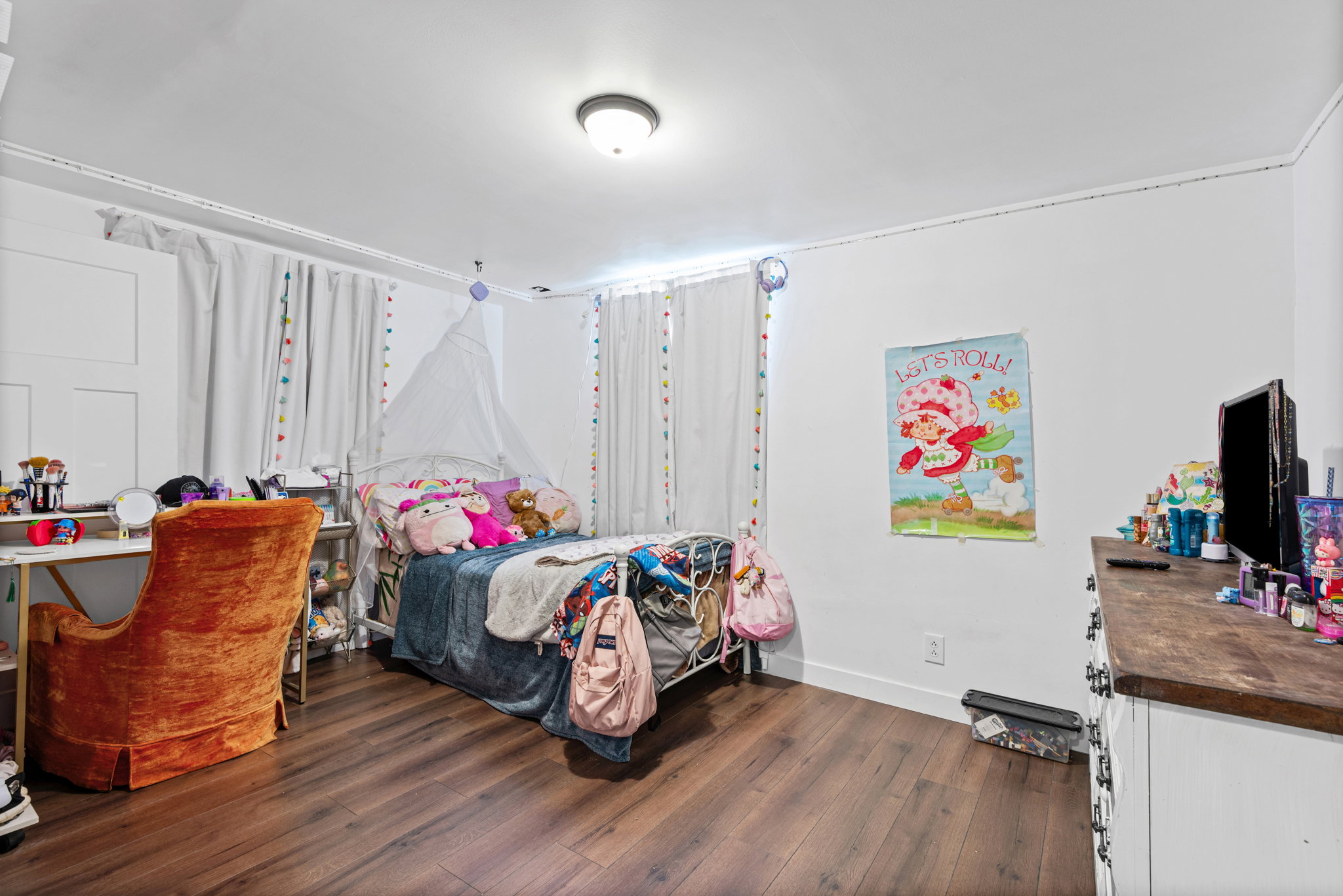 Spacious room featuring wood-finish flooring, white walls, and a recessed ceiling light fixture