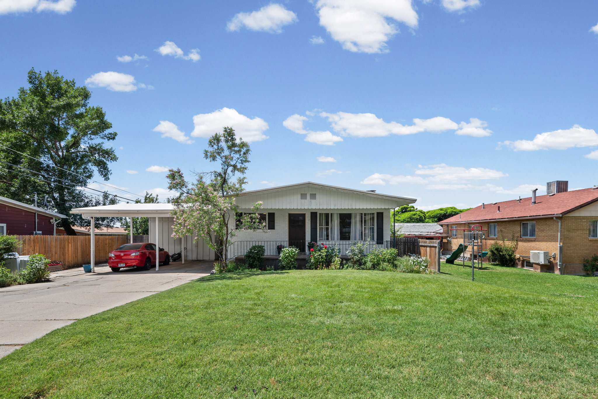 Single-story residence featuring a white exterior and a carport