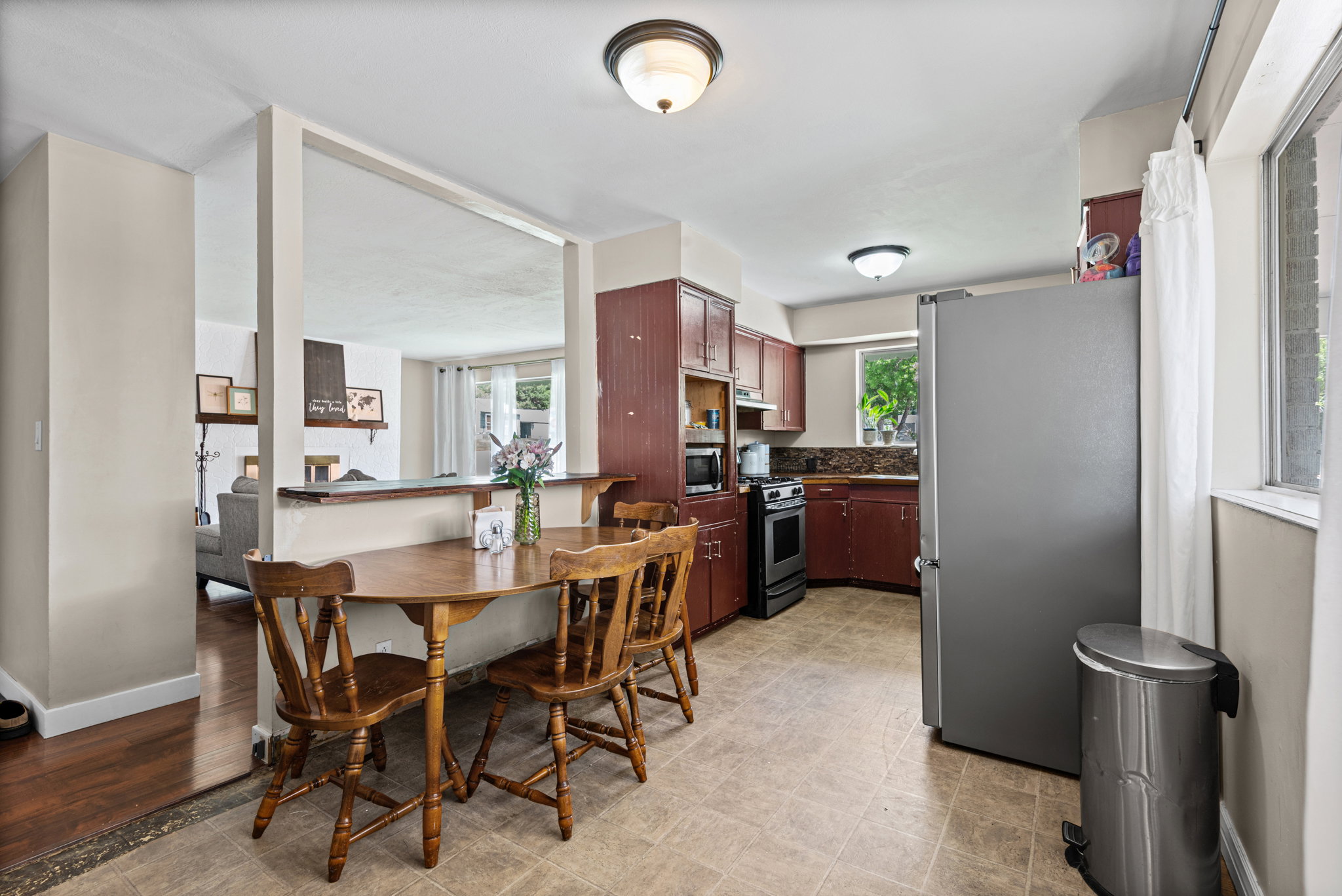 Kitchen and dining area featuring wood-finish cabinetry, tile flooring, and a stainless steel range