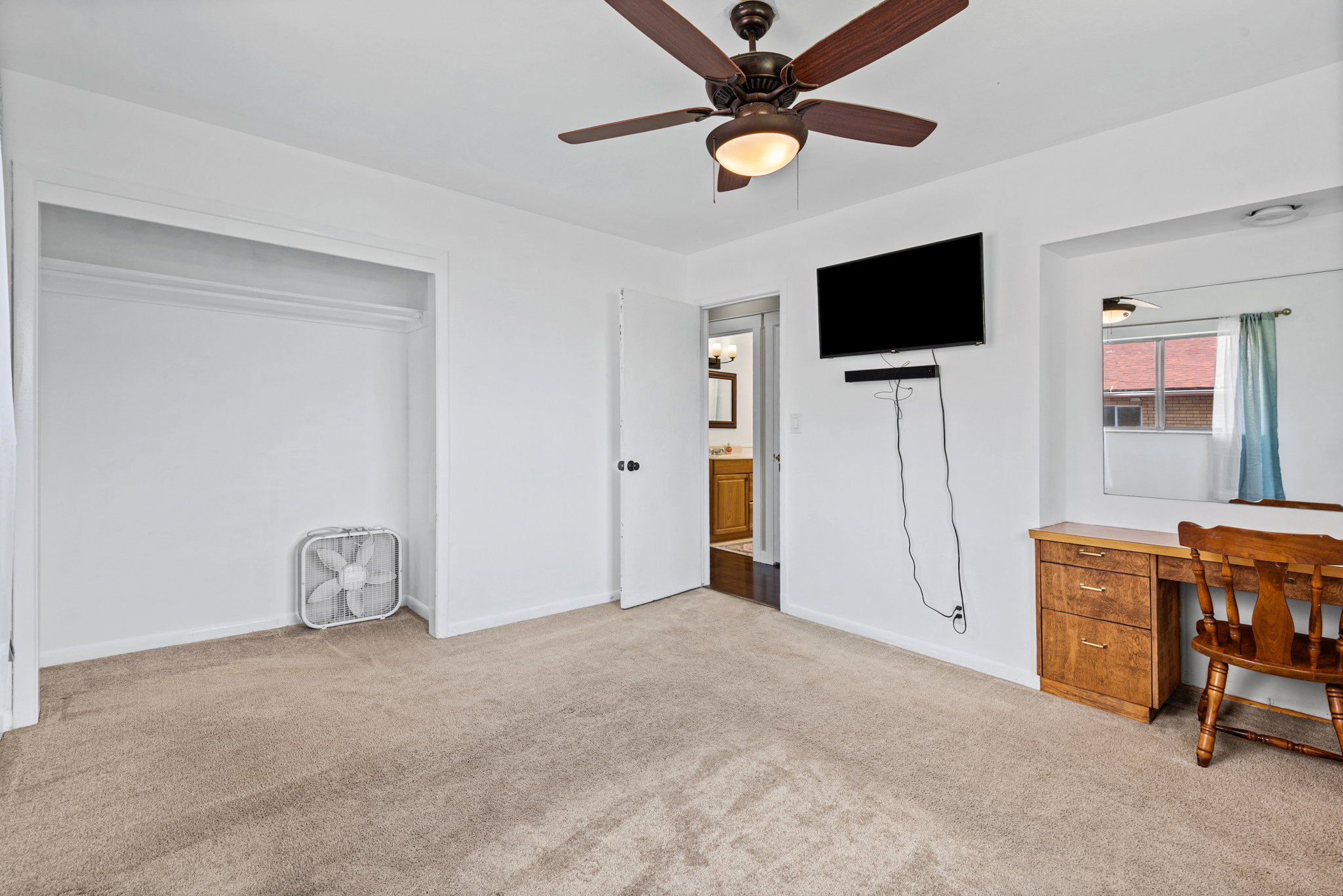Carpeted room featuring a ceiling fan with integrated lighting, a built-in closet, and a doorway opening to a bathroom