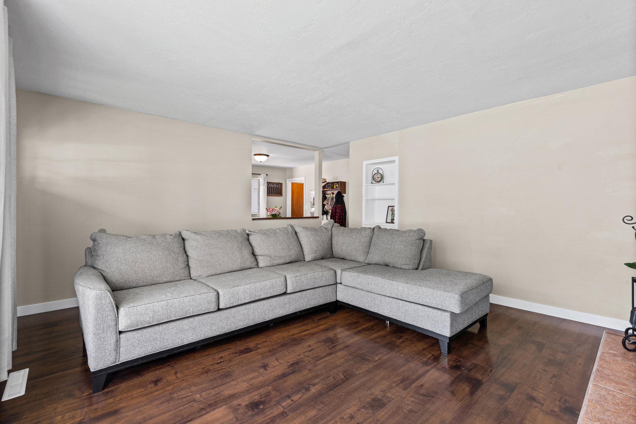 Living area featuring wood-finish flooring, light neutral-toned walls, and a recessed wall shelf