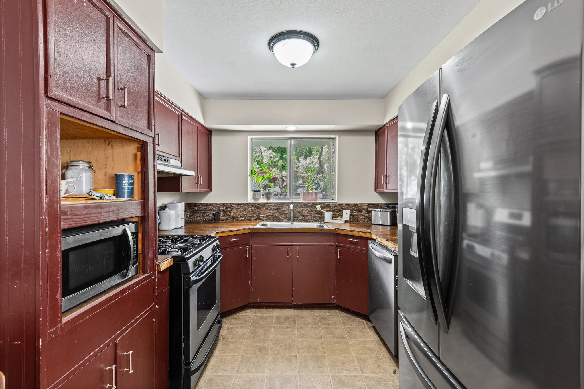 Kitchen featuring abundant cabinetry, a built-in microwave, stainless steel refrigerator, and a gas range