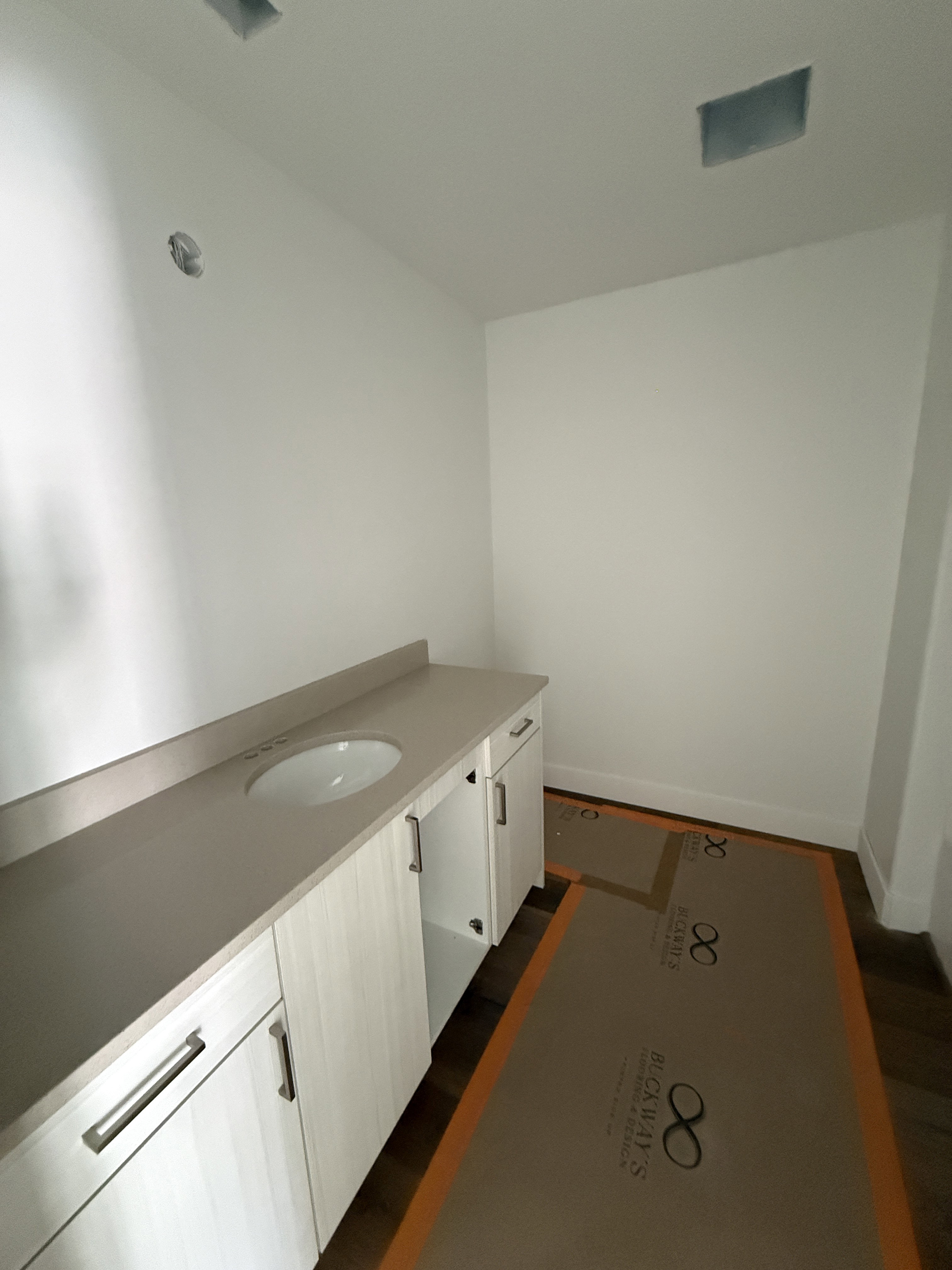 Vanity with integrated sink, light-toned countertop, and light wood-finish cabinetry featuring brushed nickel hardware