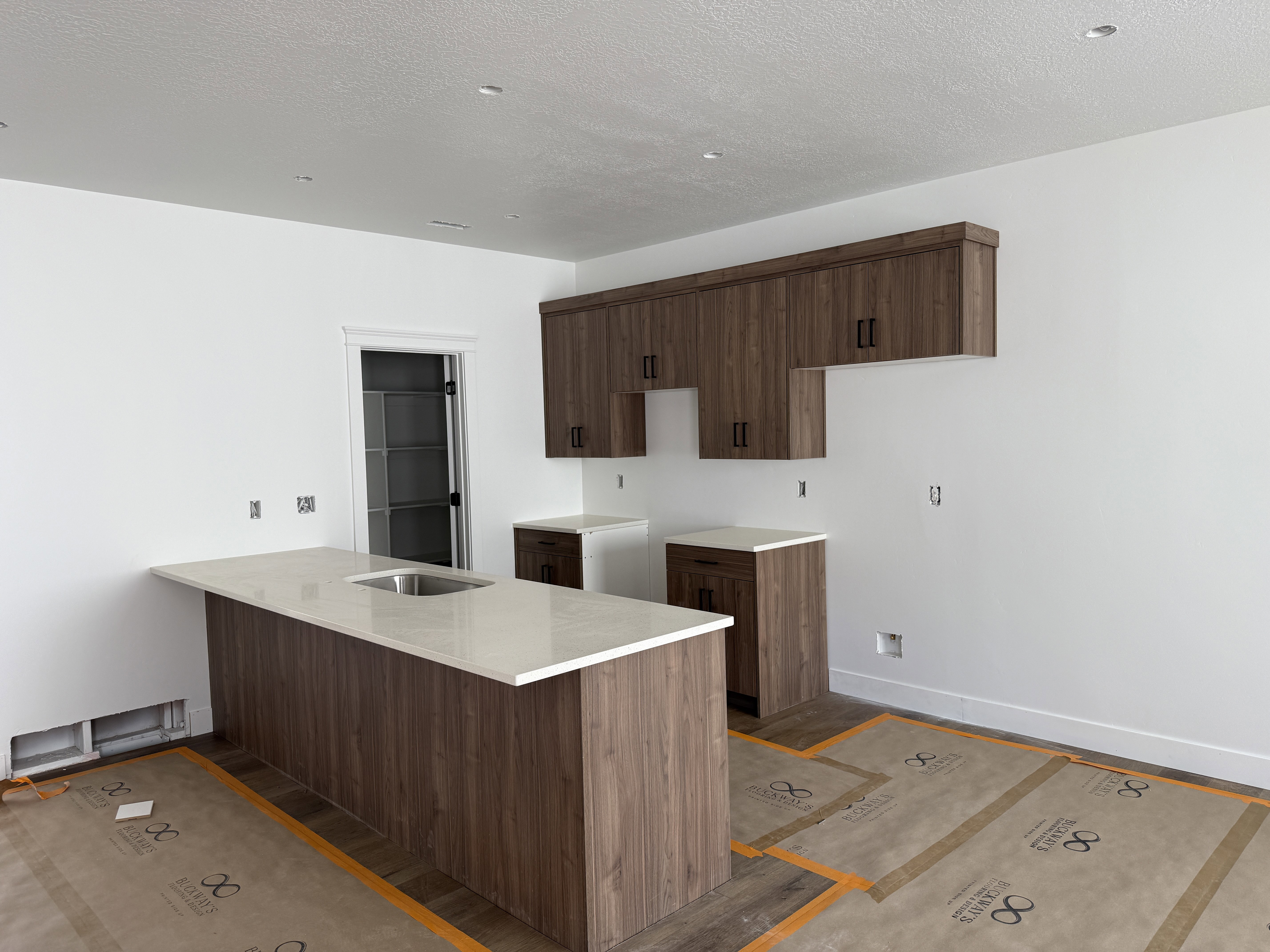 Kitchen featuring a large island with an undermount sink and light-toned solid surface countertop