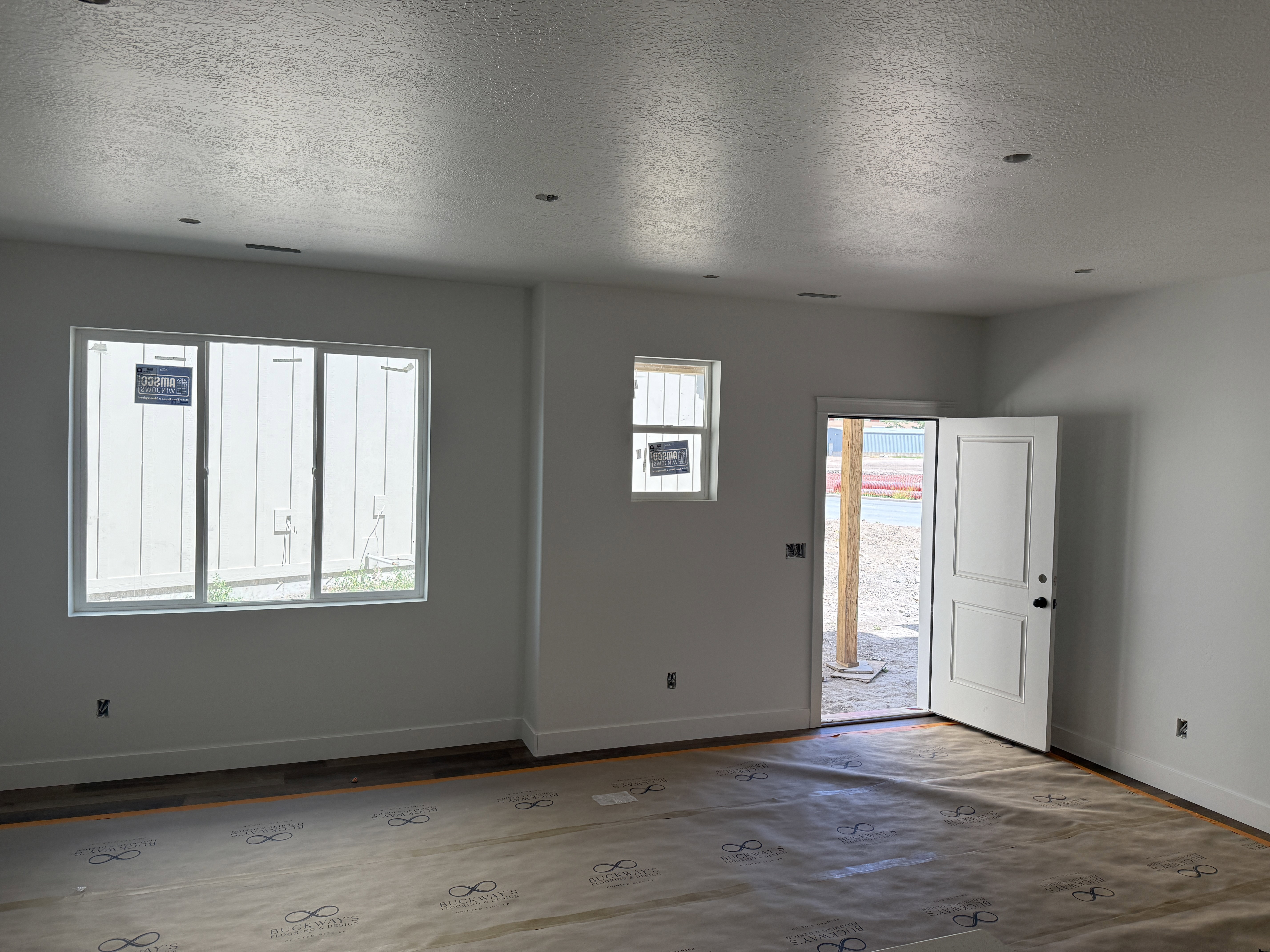 Spacious room featuring a white interior door with paneling, multiple windows, and recessed lighting
