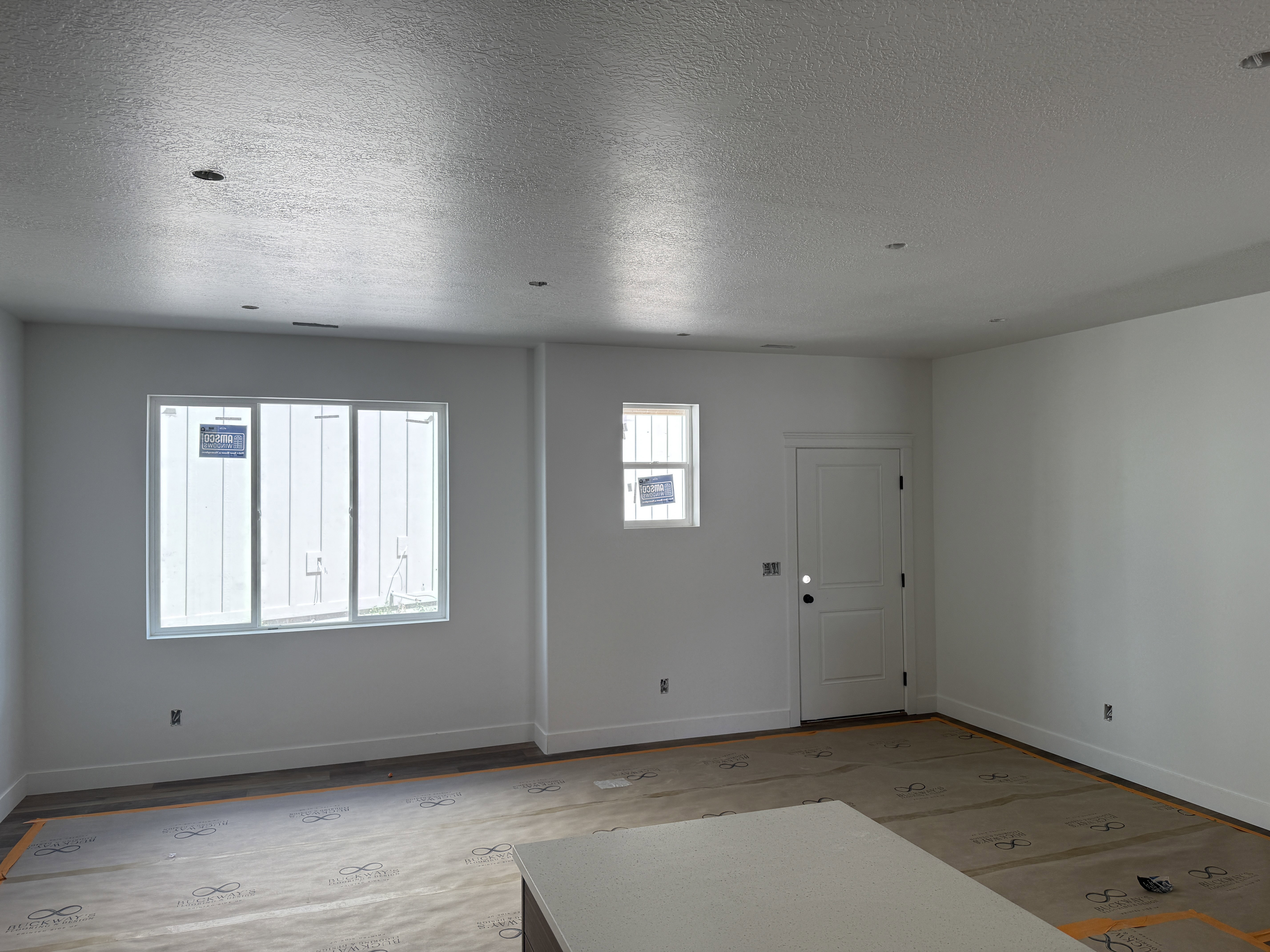 Spacious interior with recessed lighting, large windows, wood-finish flooring, white walls, and a built-in counter surface