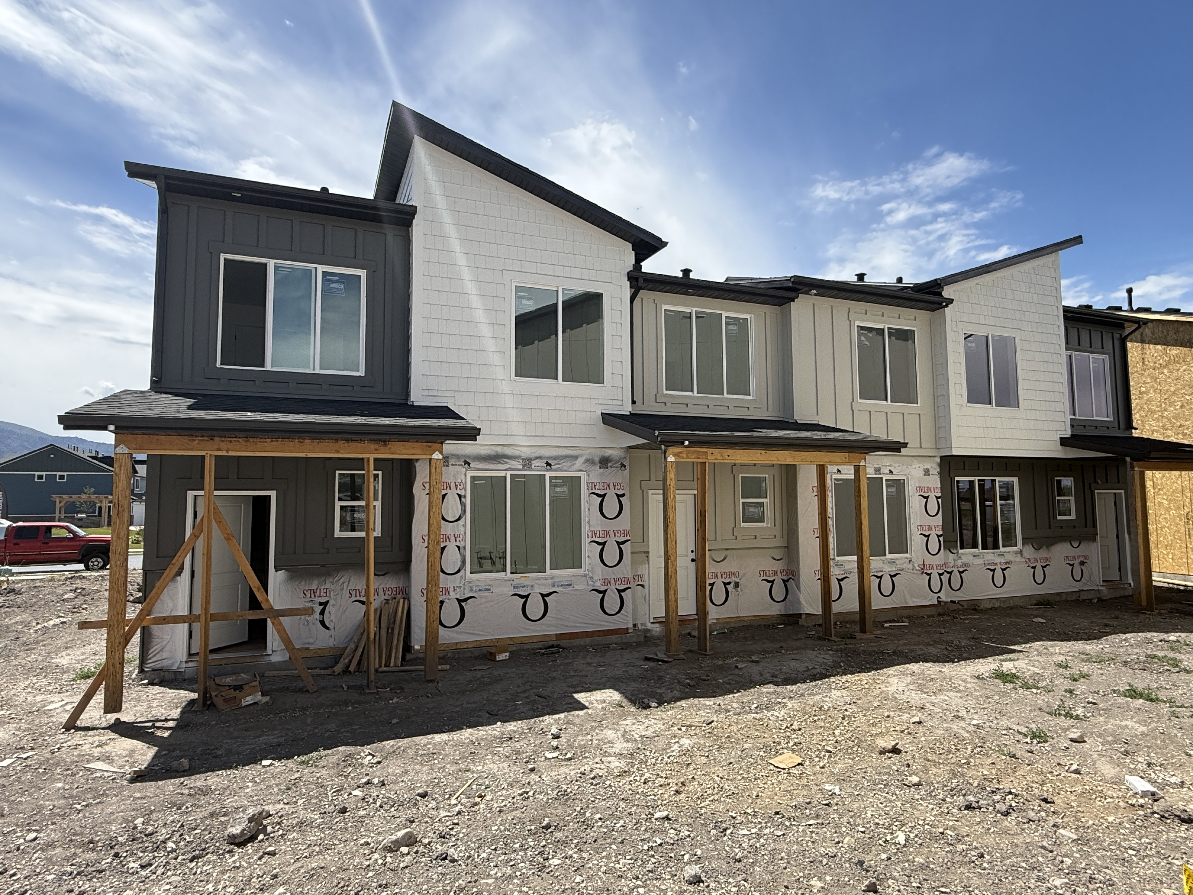 New construction townhome featuring a multi-toned facade with dark gray vertical siding and light-colored horizontal and shake siding