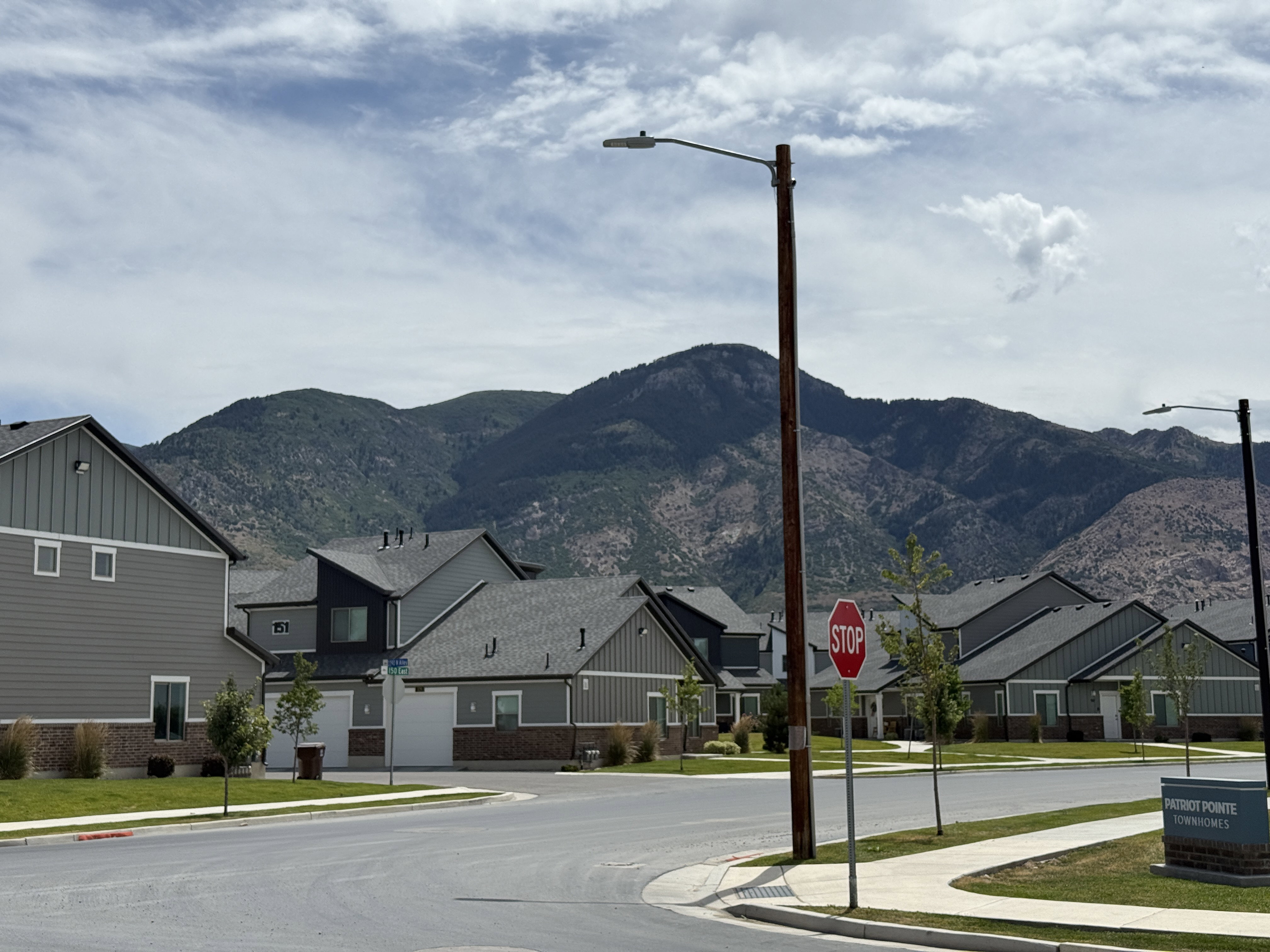 Modern residential architecture with a mountain backdrop, featuring contemporary siding and brick accents