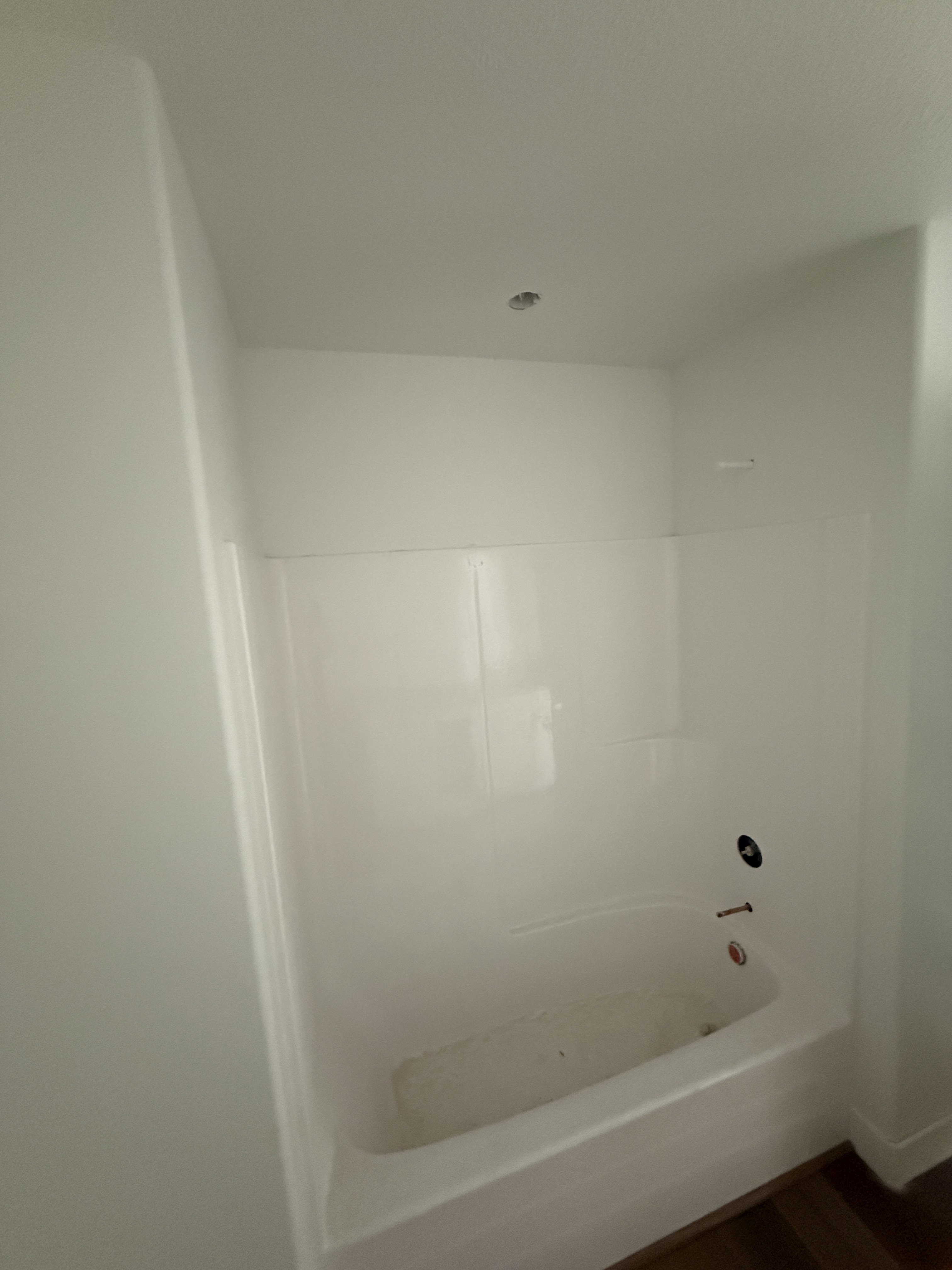 White bathtub and shower surround with dark plumbing fixtures