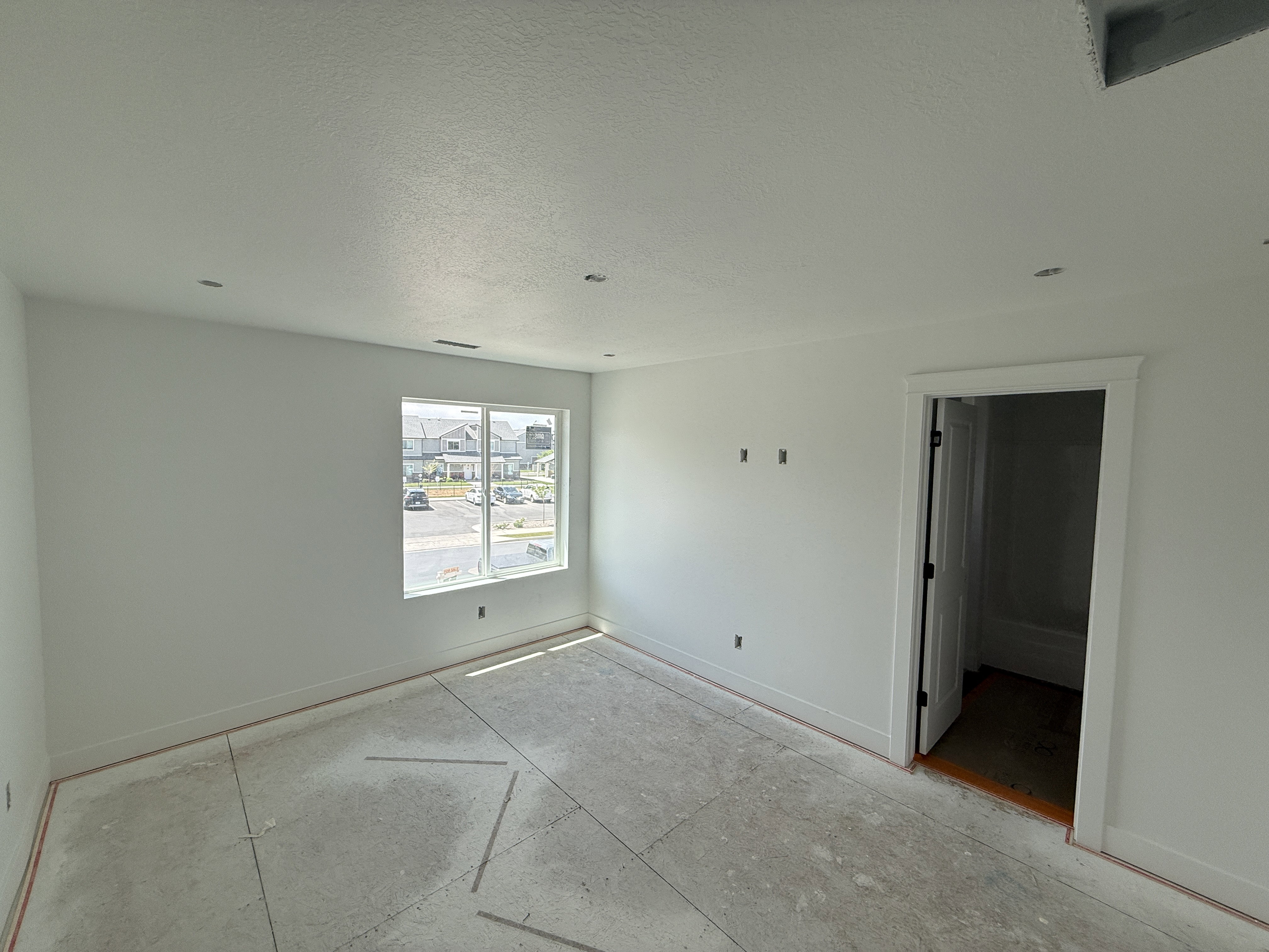 Bright room with a large window, recessed lighting, and a white interior door with dark hardware