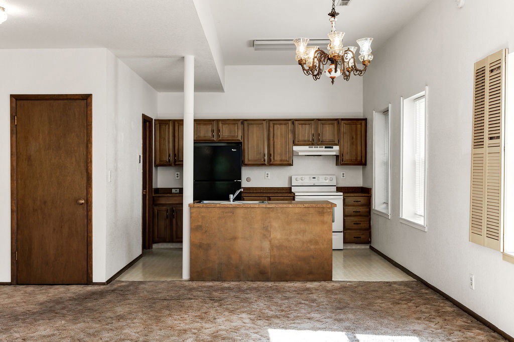 Kitchen area featuring wood-finish cabinetry, a white range, and a black refrigerator
