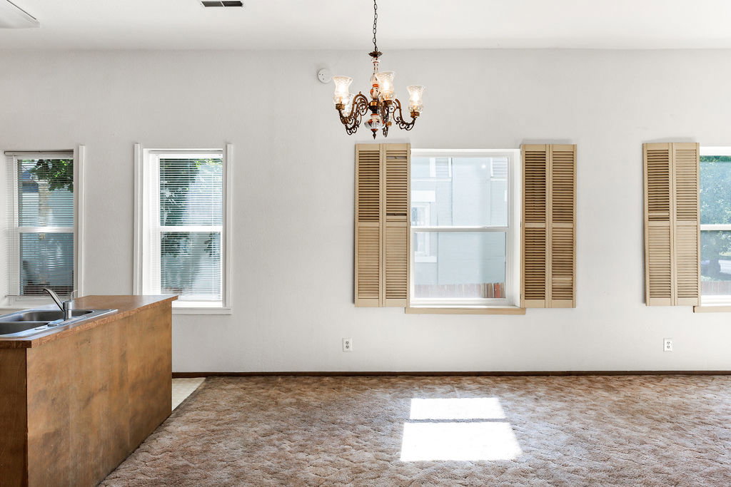 Open-concept living area with a built-in wood-finish breakfast bar, multiple windows, and a decorative chandelier
