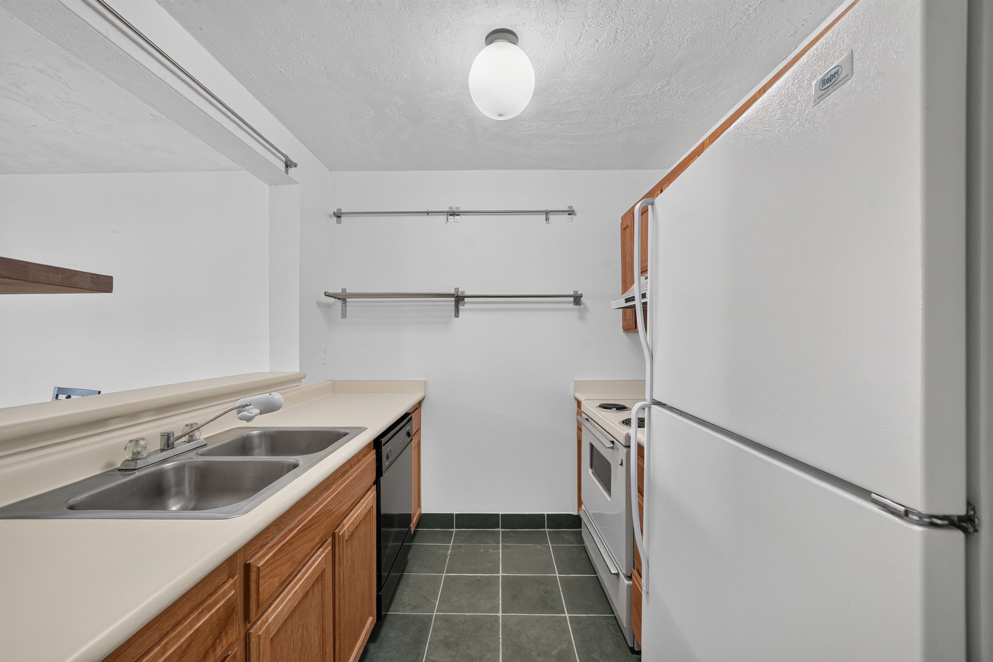 Kitchen featuring wood-finish cabinetry, a double basin stainless steel sink, a dishwasher, and a range with an oven