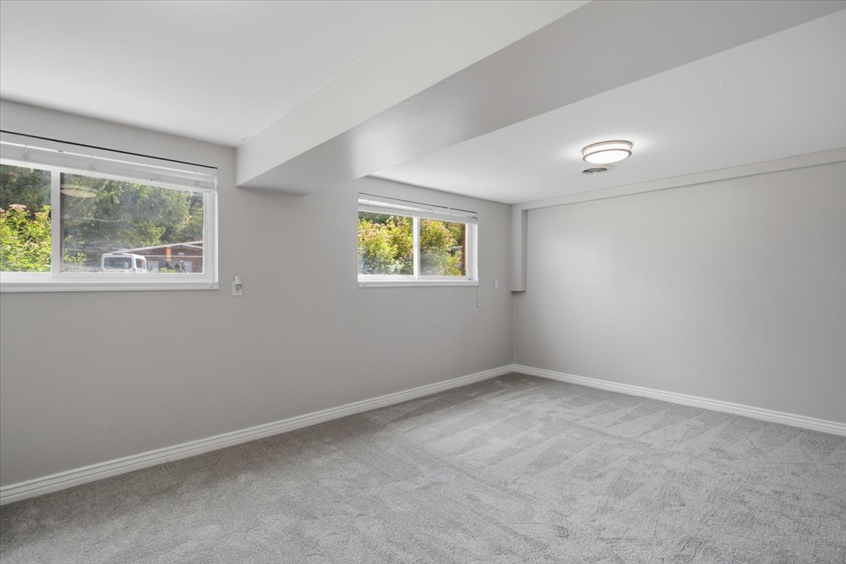 Room featuring light gray walls, gray patterned carpet, and white baseboards