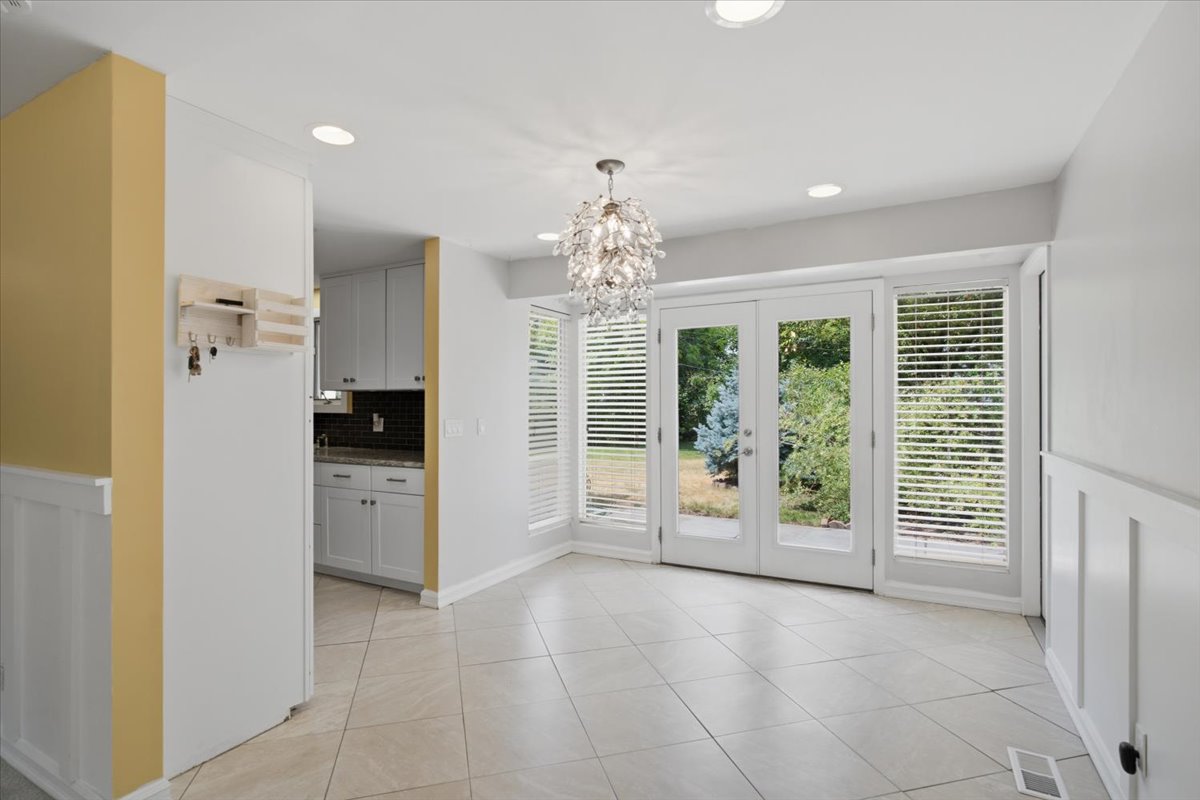 Dining area featuring ceramic tile flooring, a contemporary chandelier, recessed lighting, and white wainscoting