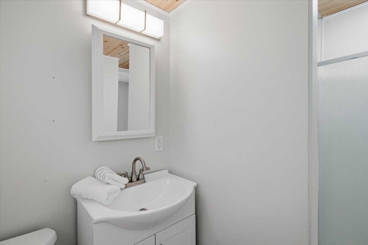 Bathroom vanity with a white basin sink, brushed nickel faucet, and a rectangular framed mirror
