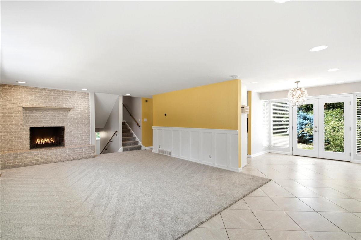 Spacious living area featuring a light-colored brick fireplace, recessed lighting, and a multi-tiered crystal chandelier