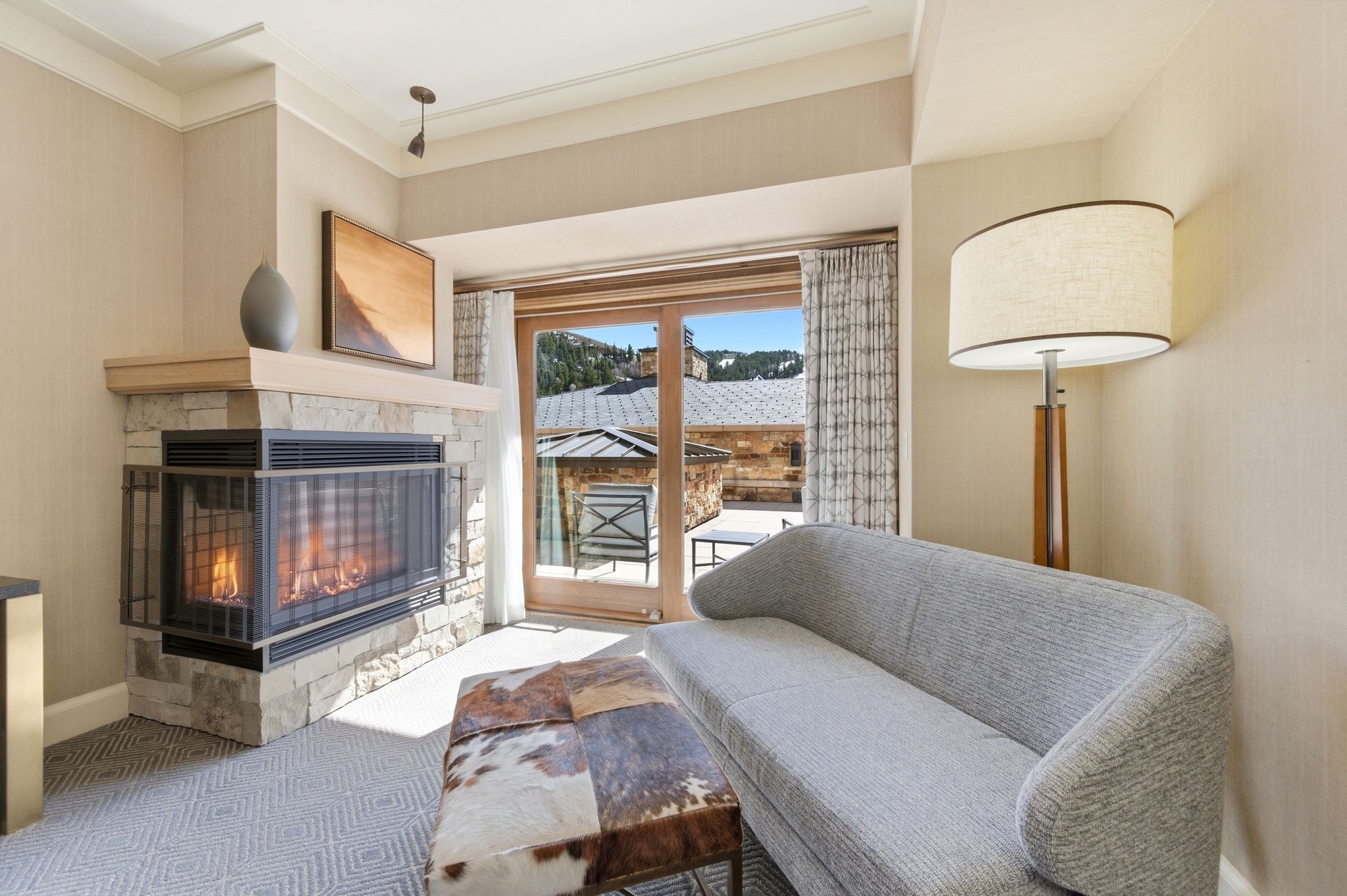 Stone-clad fireplace with a light-toned wood mantel and integrated fire screen