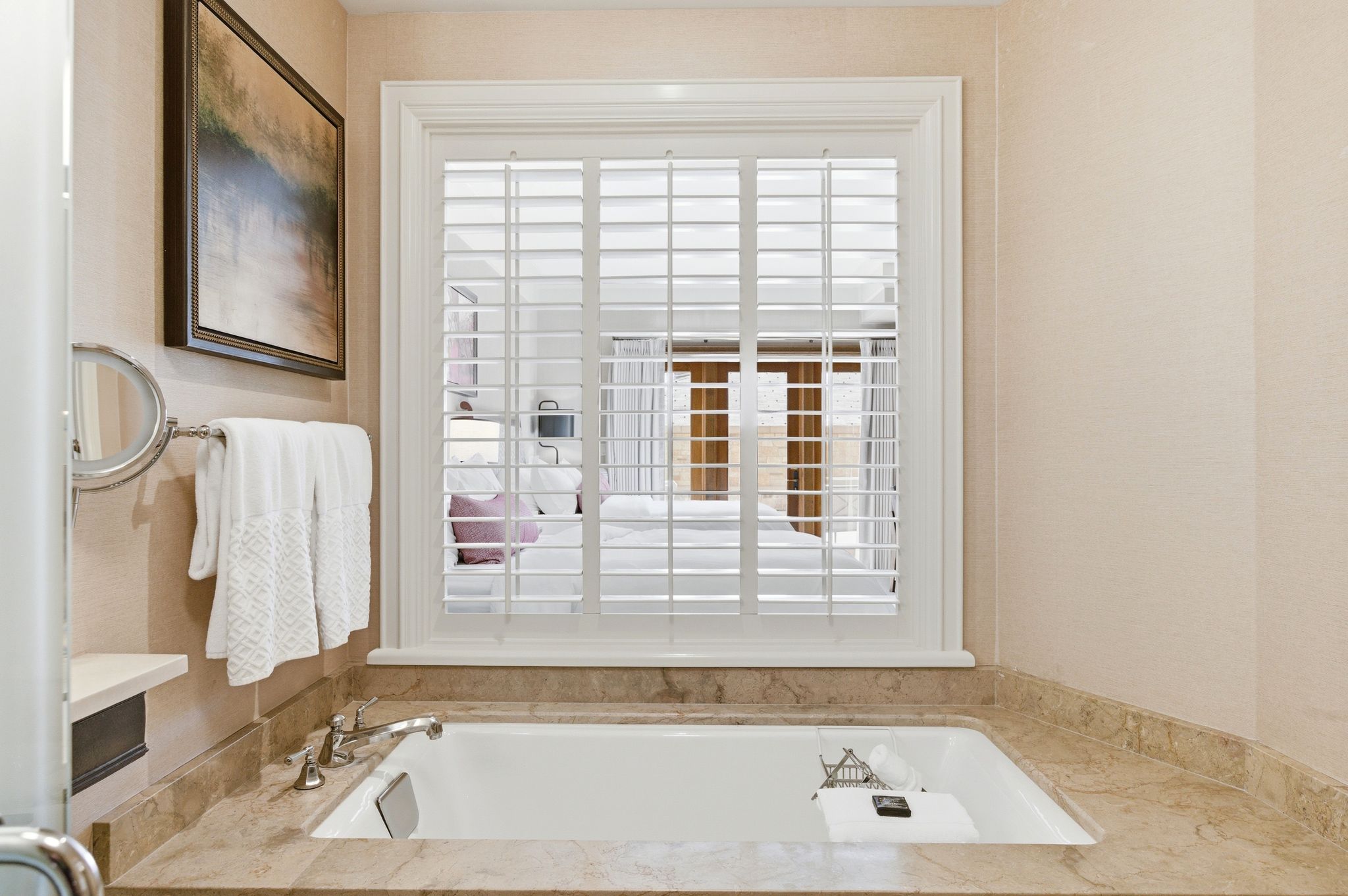 Built-in soaking tub featuring a stone-look surround and deck-mounted fixtures