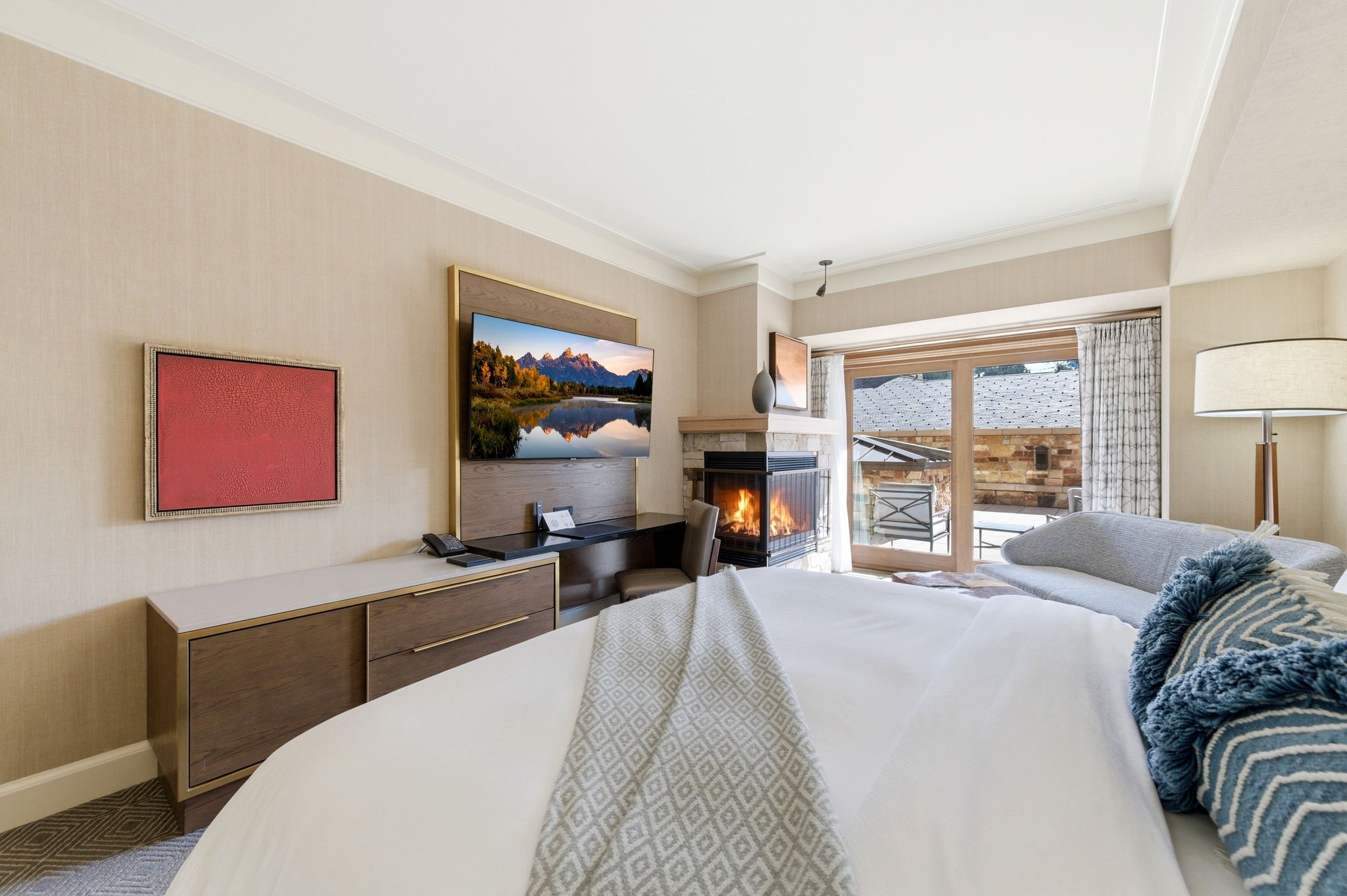 Bedroom featuring a gas fireplace with stone surround, wood-finish flooring, and direct access to an outdoor patio through glass sliding doors