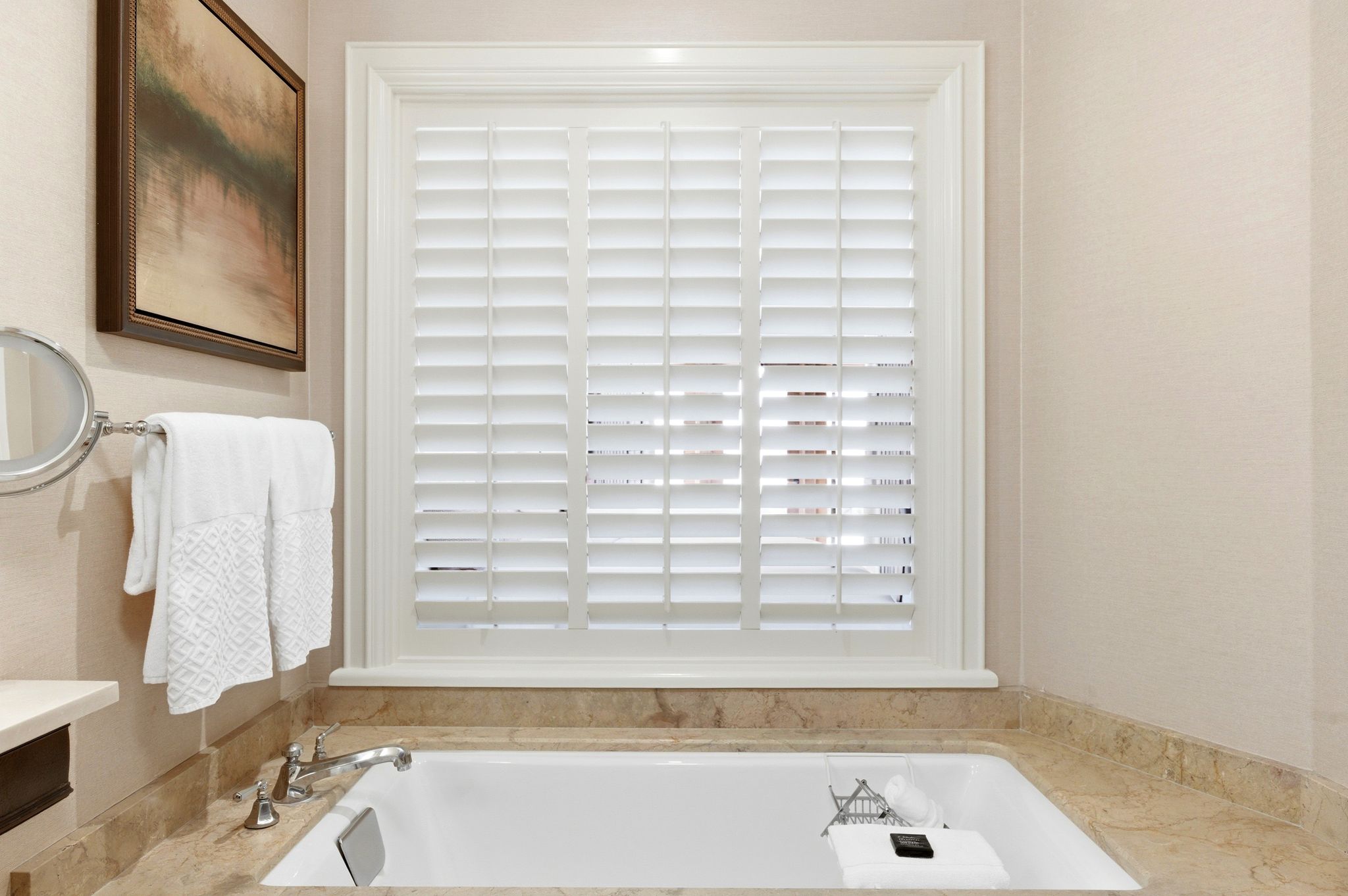 Built-in soaking tub with a polished chrome deck-mounted faucet, surrounded by a natural stone countertop and matching backsplash